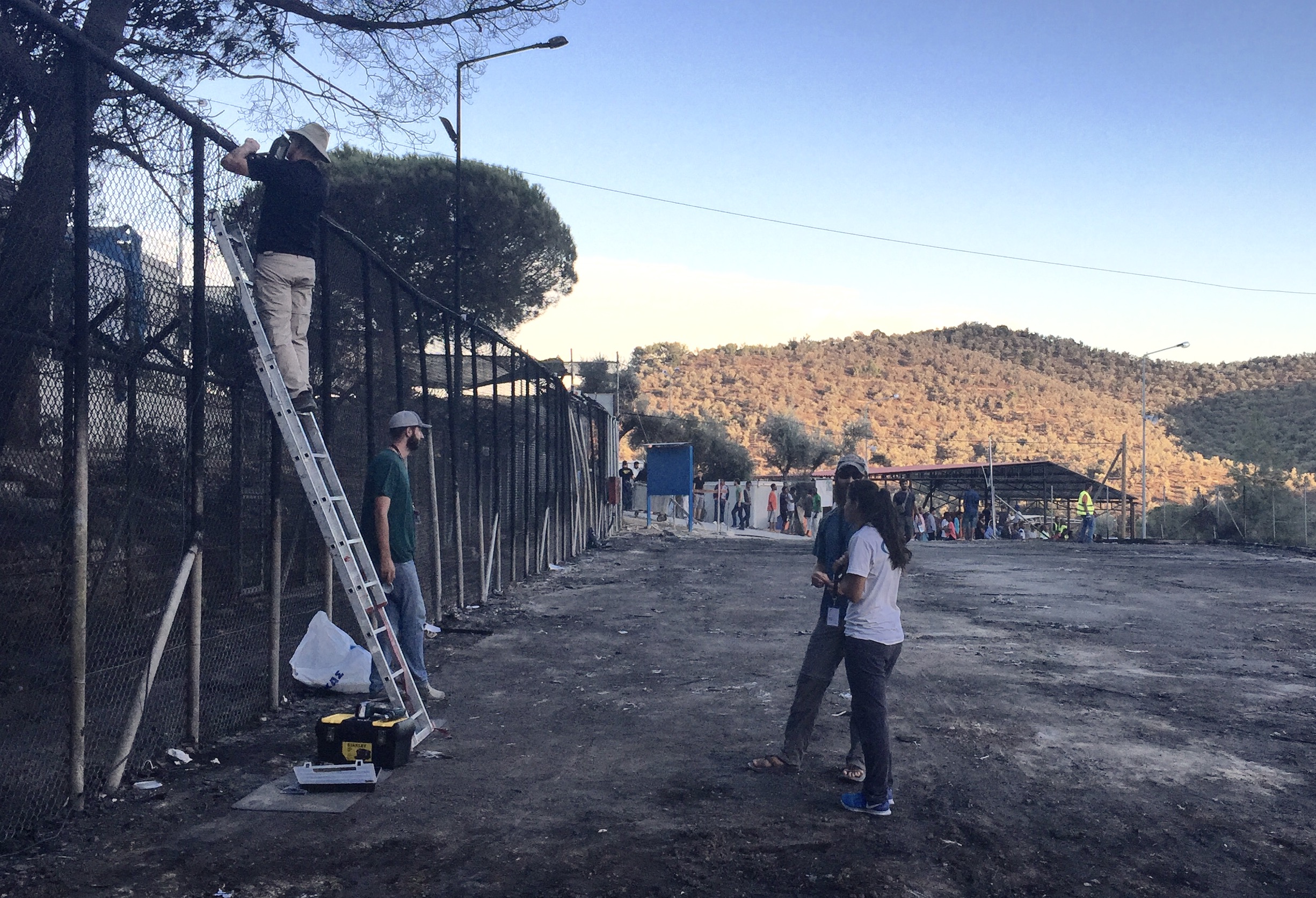  Volunteers fix a burnt barbed wire fence along the perimeter of the camp.&nbsp; 