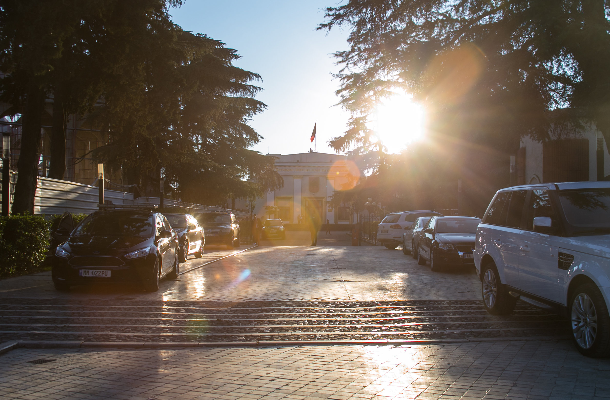  An Albanian Government building sits at the end of a guarded drive as the sun sets. 