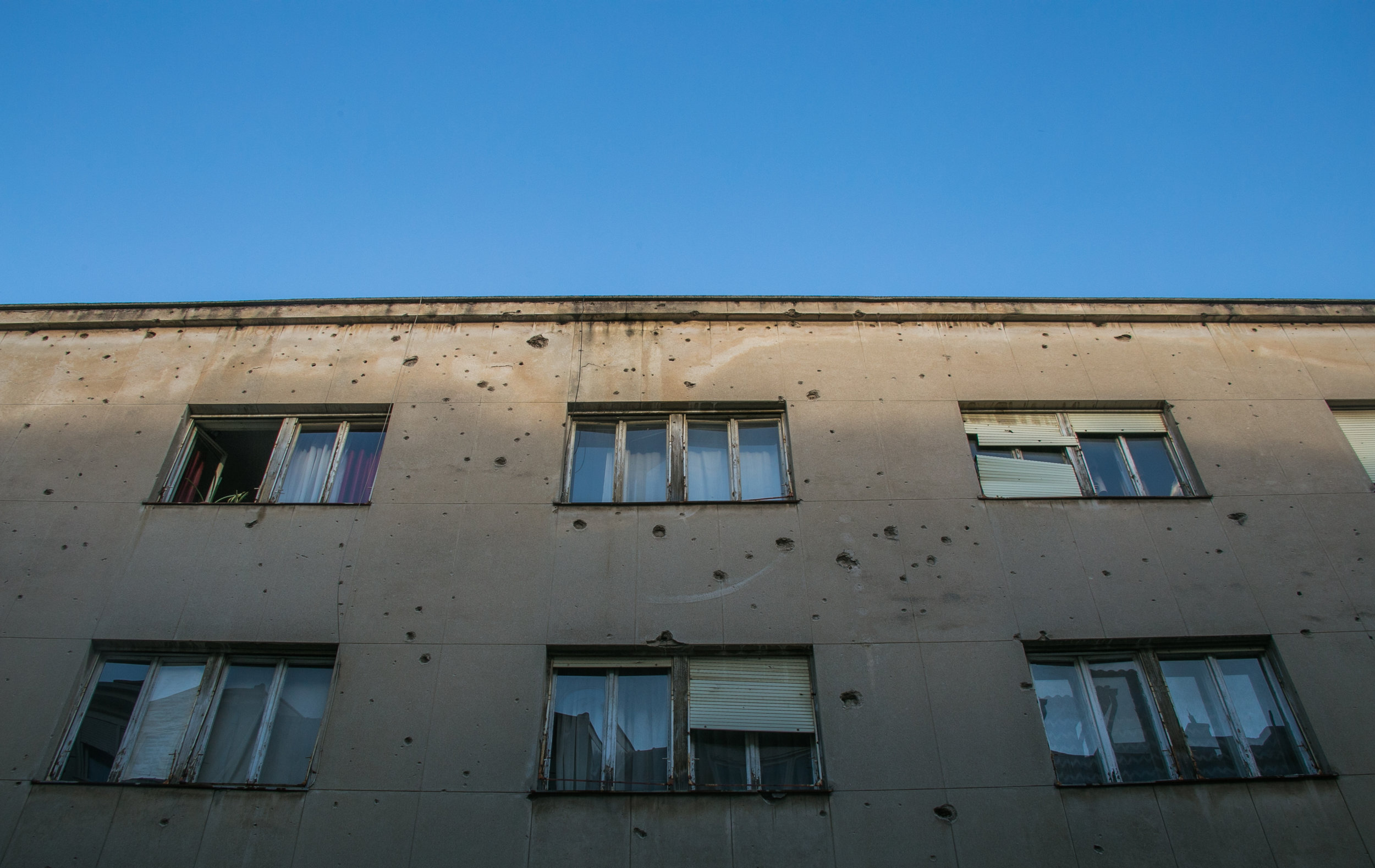  Bullet holes riddle the side of an apartment building in Mostar, Bosnia. The city served as a battle front between Croatian and Republic of Bosnia forces (just one of many racial battles) during the much larger Bosnian War. The two sides battled for