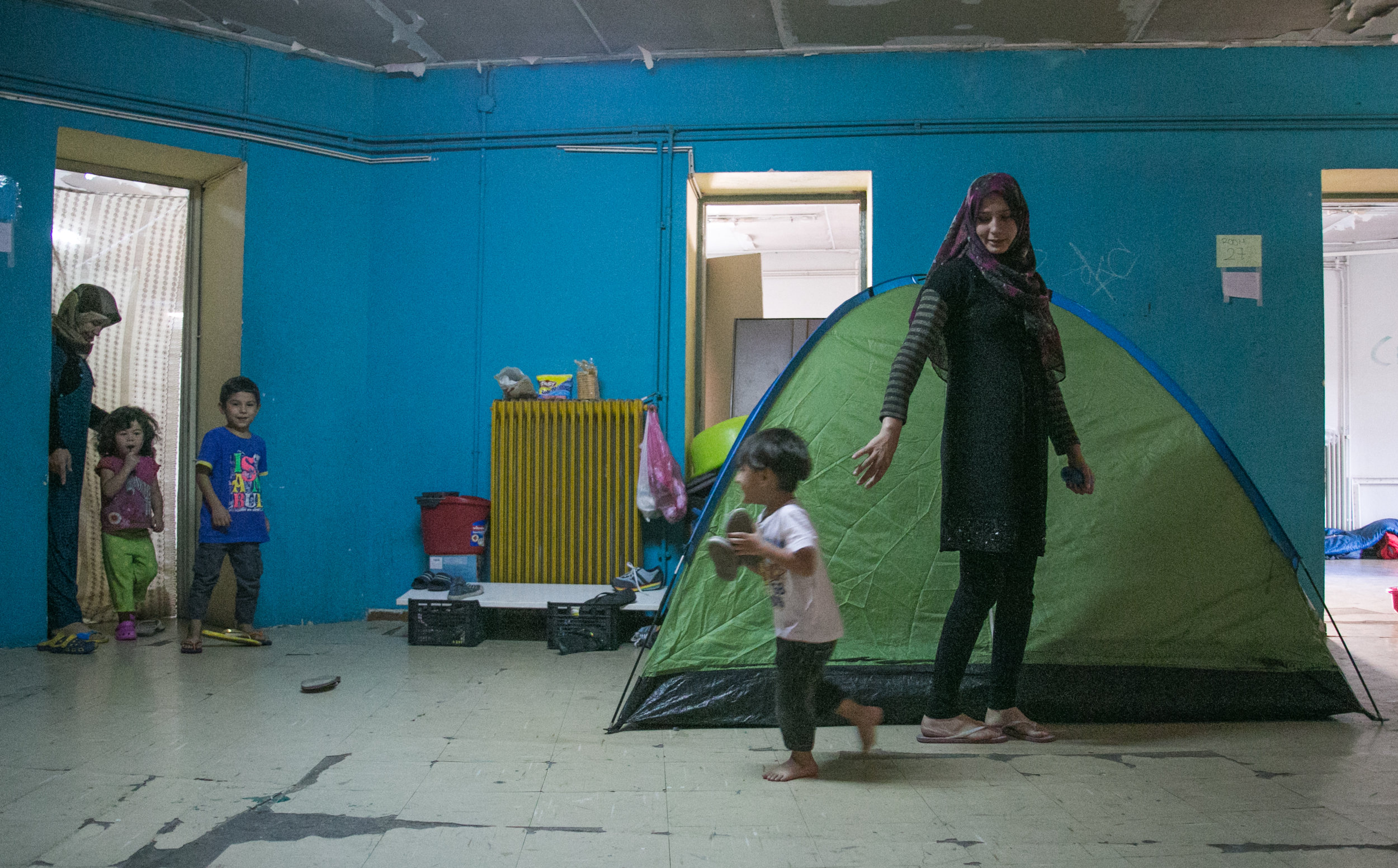     10/19/16 - Ali Alowi and his mother walk through the dark hallway of the third floor corridor. Tents take up any free space available in the school as refugees attempt to escape the dangers of the streets.&nbsp; 
