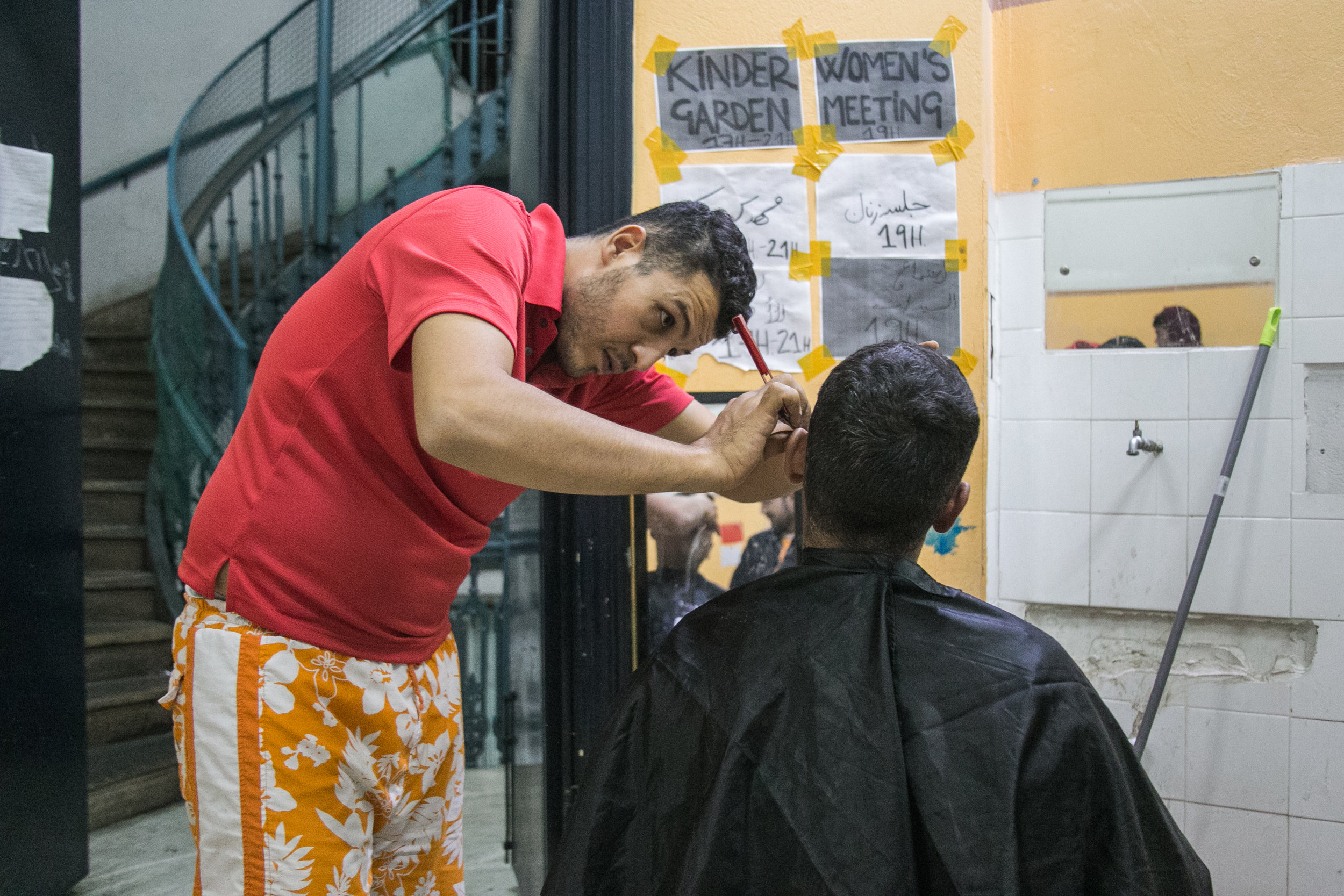  The Jasmine School barber cuts a man's hair in the hallway of the second floor. Haircuts are three euro. 