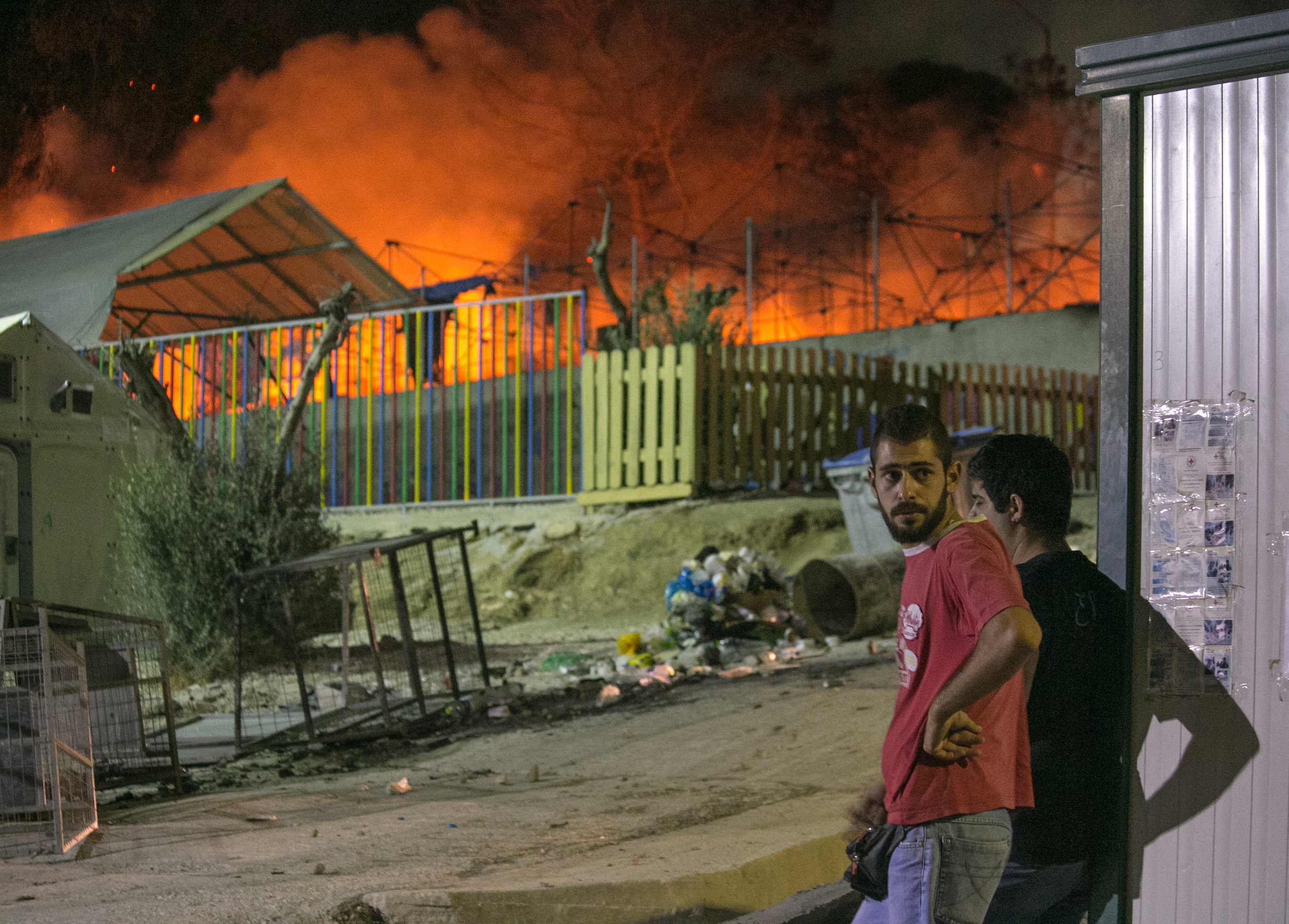  09/19/16 - 9:30pm: Migrants watch on as the Moria refugee camp burns to the ground. ©Mike Schwarz/AP 