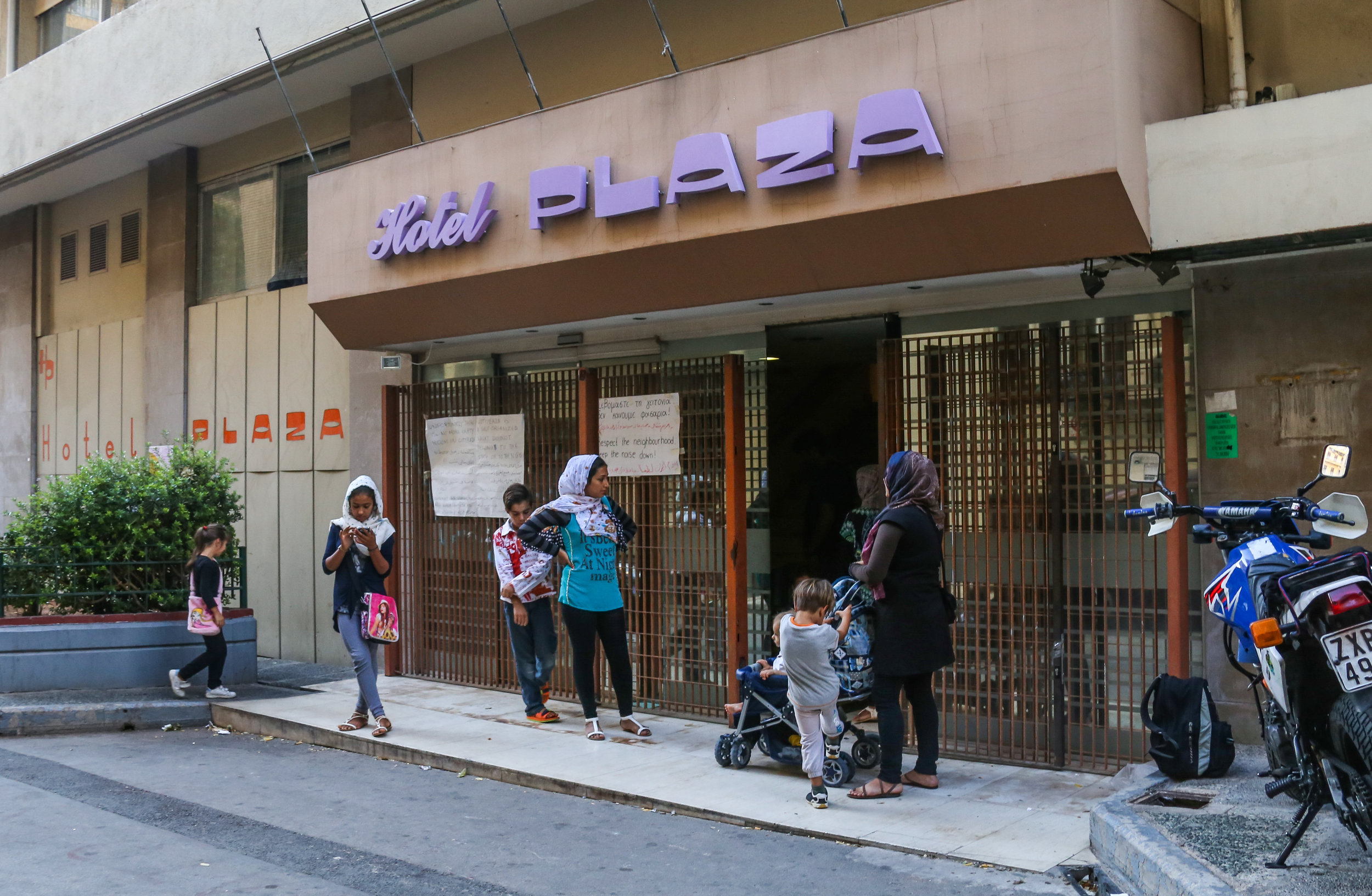  09/24/16 - 2:00pm: Mothers and their children stand outside while the lobby of City Plaza Refugee squat is cleaned. The abandoned 7-story hotel now houses 400 migrants (180 of those children). 