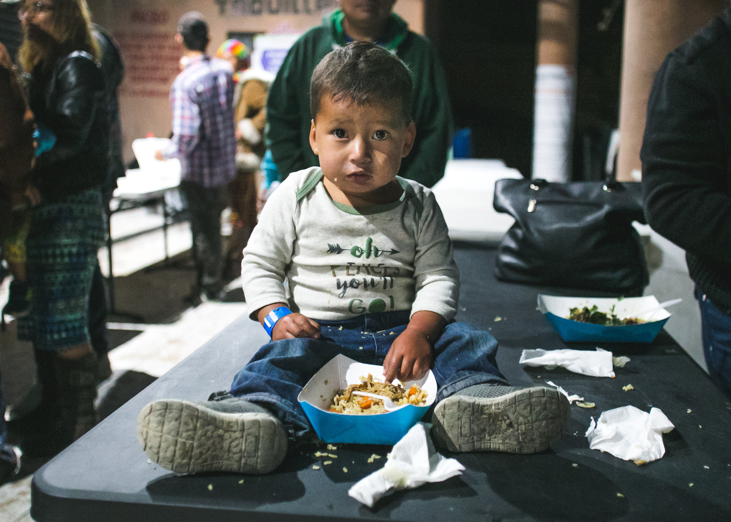  David Zuniga, 2, of Honduras, sits on a dinner table in the Barretal migrant camp located 20 minutes outside of Tijuana. Three meals a day are provided by local volunteers, churches, or international non-profits. David is covered by a dinner served 