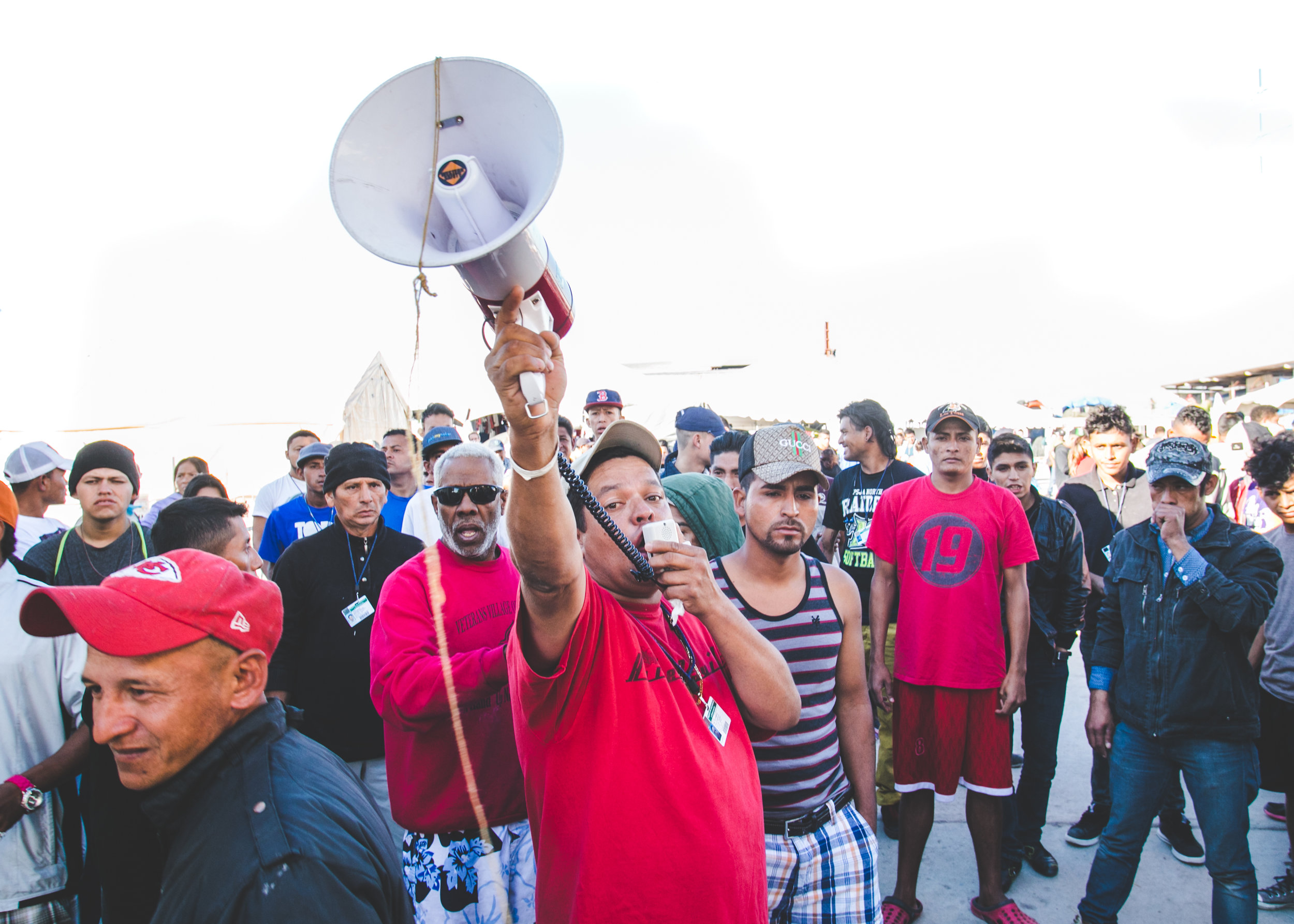  A man attempts to calm an angry crowd of refugees after a fellow camper was arrested for selling cigarettes to minors. The crowd began following police out of the facility after the arrest was made. They were stopped at the front gate - and eventual