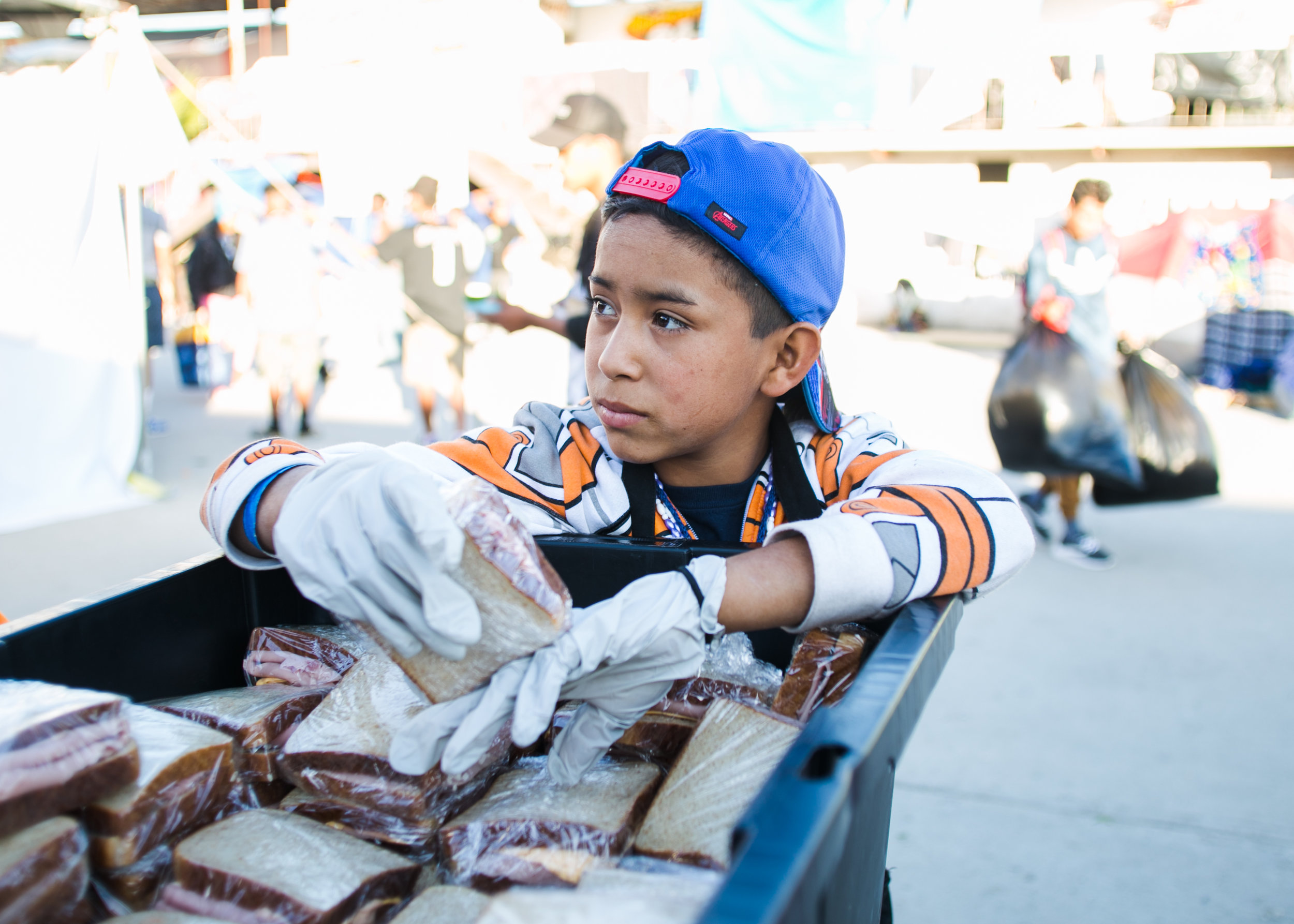  A Honduran refugee gives out sandwiches prepared by World Central Kitchen in the Barretal refugee camp located just outside of Tijuana, Mexico. 