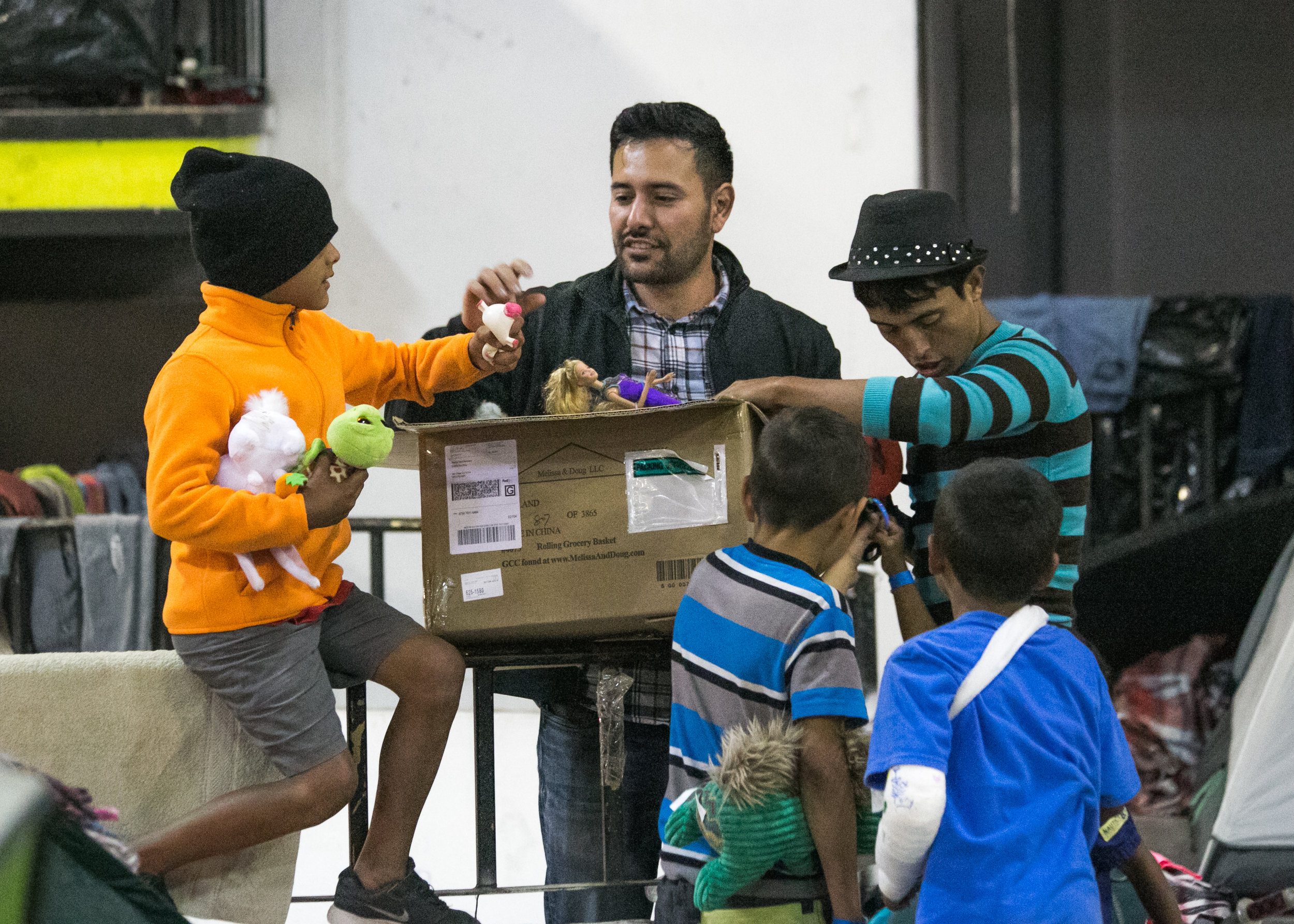  Volunteer, Rodrigo Rodriguez, of San Diego, hands out toys to refugee children in the Barretal camp located in Tijuana, Mexico. Rodrigo also purchased a washer and dryer for the facility.  