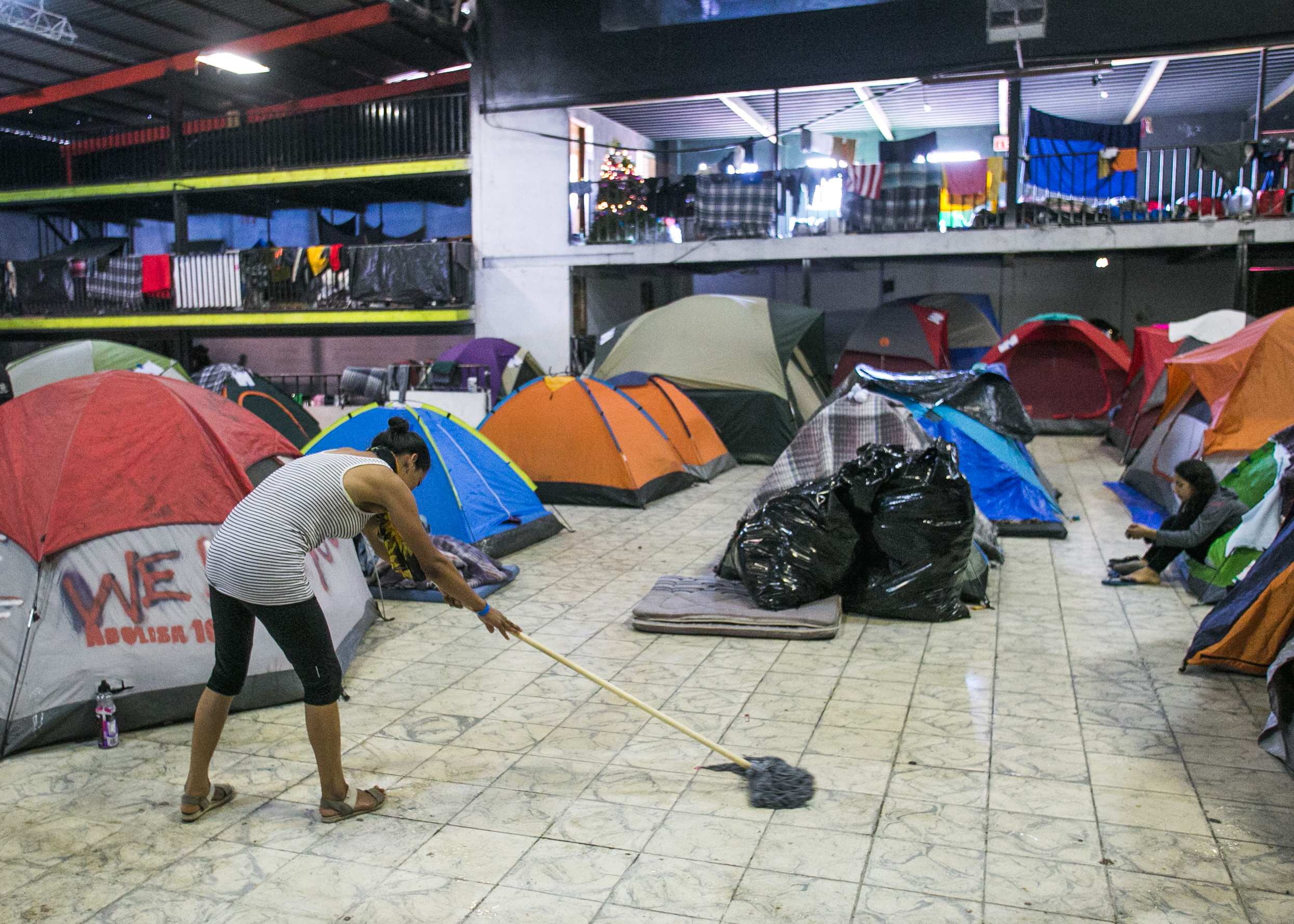  A refugee cleans the floors of the family section inside the Barretal compound located in Tijuana. Mexico. 