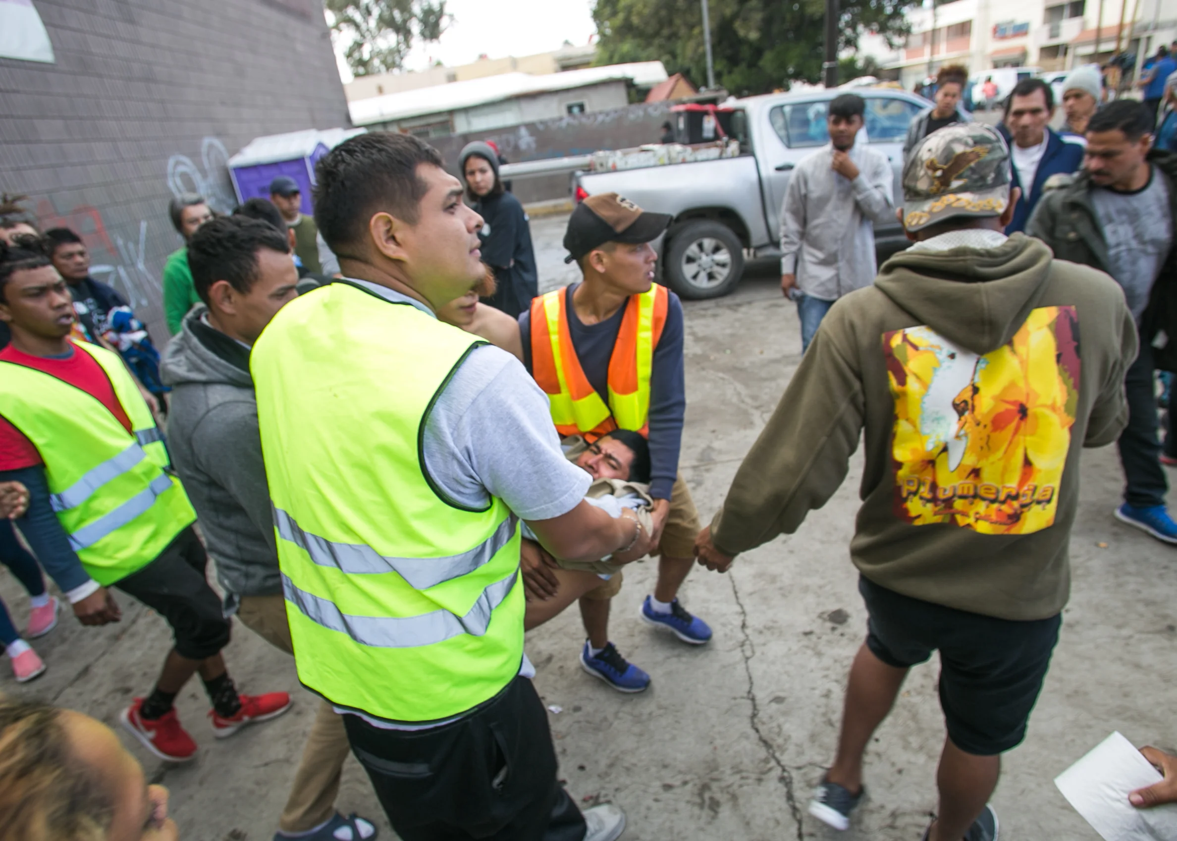 A man is carried out of the El Chinchetta refugee compound in Central Tijuana. He began seizing and vomiting due to a lack of medication according to responders on scene. Medical services were suspended in the facility several days prior in an effort to close the compound. Care from independent non-profits slipping past the police-guarded entrances is all that remain. Recent complaints from community members in Central Tijuana have lead to the government relocating migrant camps to low-income suburban communities on the outskirts of Tijuana.