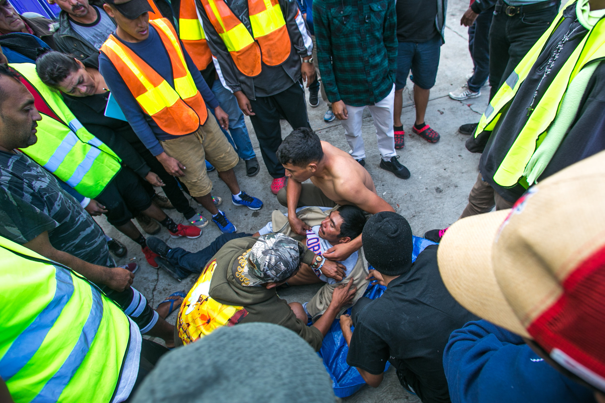  A man receives rudimentary medical attention from other migrants while waiting for emergency services. He began seizing and vomiting due to a lack of medication according to responders on scene. Medical services were suspended in the facility severa