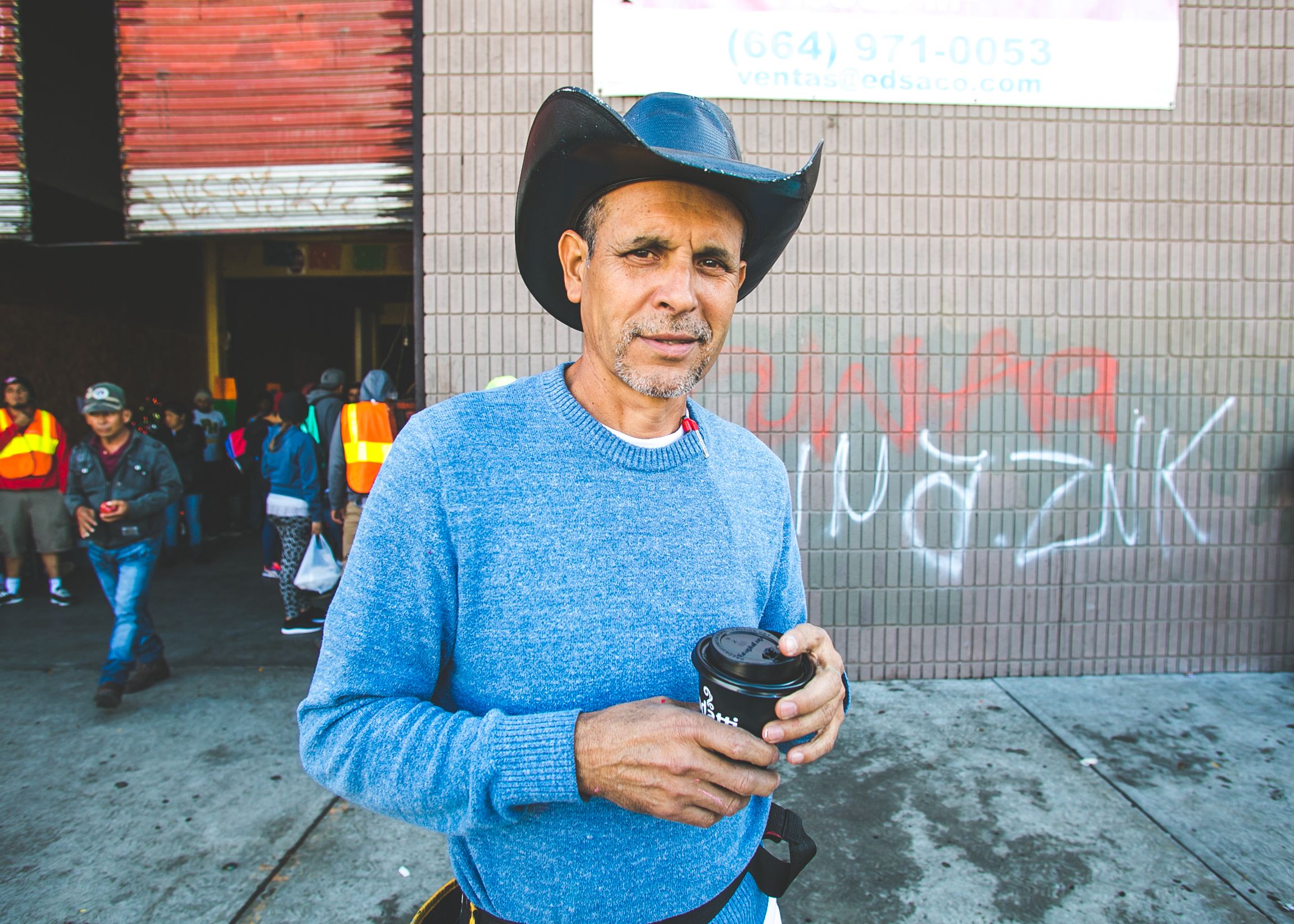  Volunteer and San Diego artist, Robert Marquez, stands outside the El Chinchetta refugee compound in Central Tijuana. Robert beautifies these temporary living spaces by painting sheets that he hangs on the walls.  