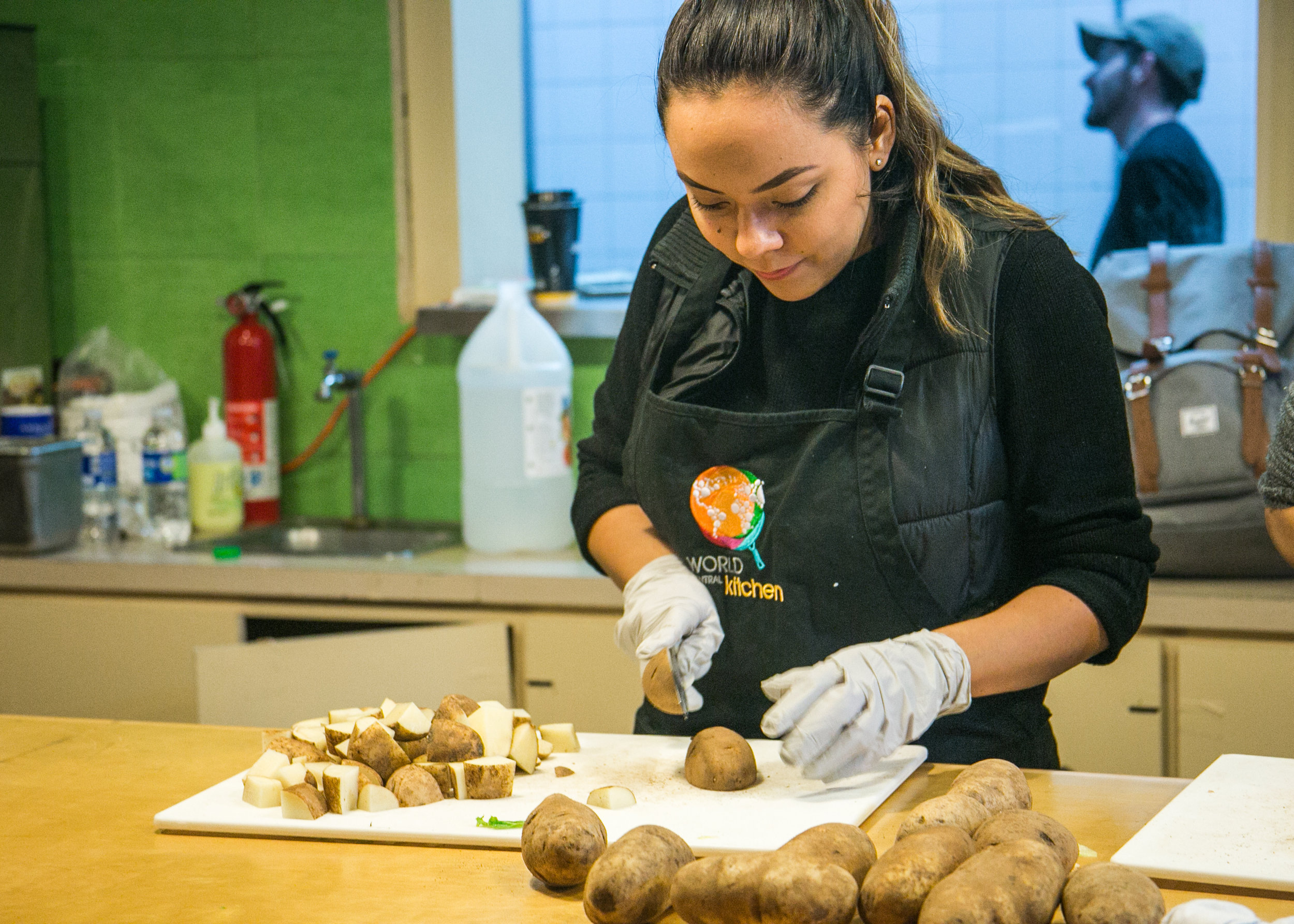  A World Central Kitchen volunteer chops potatoes in preparation for dinner at the new World Central Kitchen headquarters in Tijuana, Mexico. The donated kitchen was once a famous restaurant known for being the birthplace of the burrito. Now it house