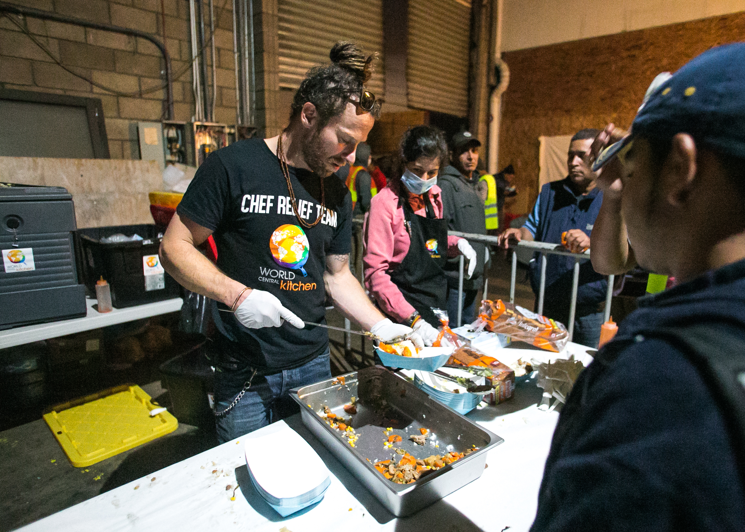  Project Leader, Sam Bloch, serves dinner to refugees living in the El Chinchetta compound in Central Tijuana. 