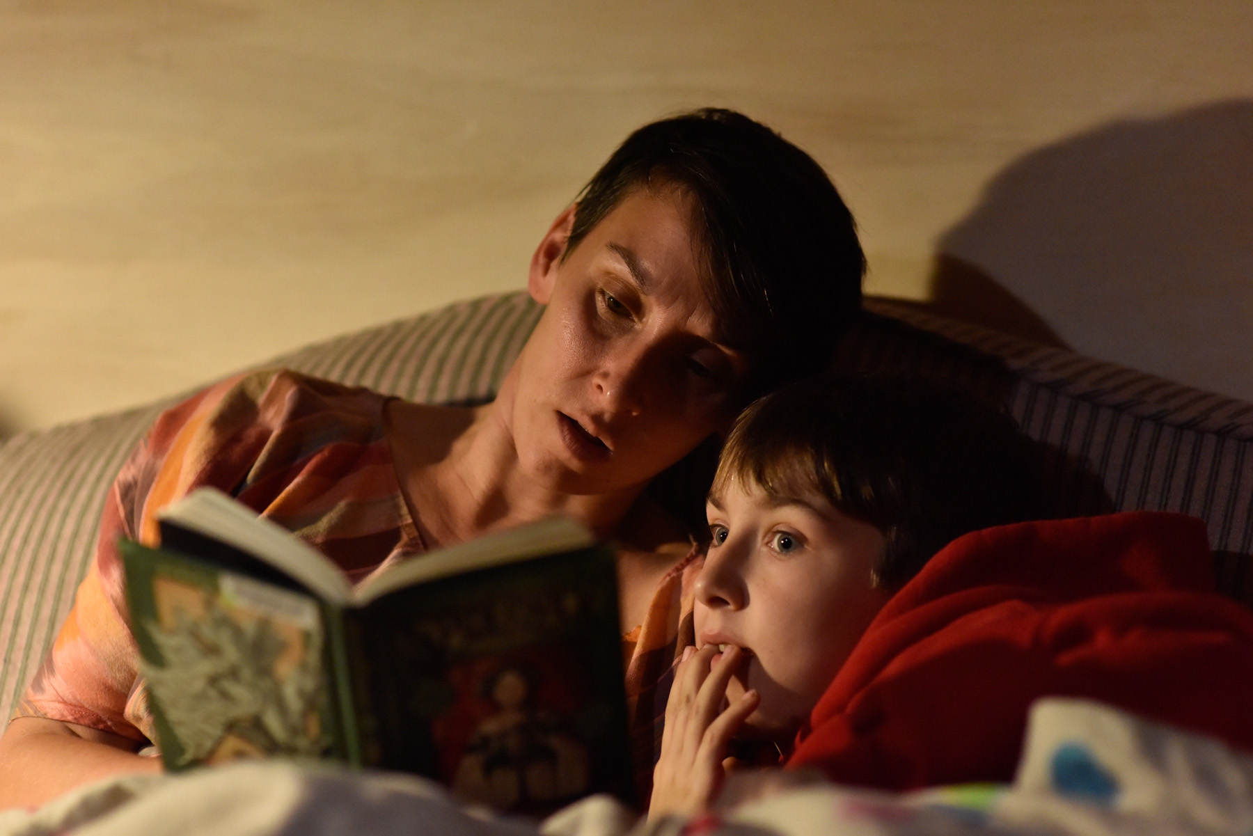 Laura Poulette reads "Spiderwick" to her son Isaac Deaver, 8, before bedtime. Laura doesn't take part in her son's traditional home-schooling, but she teaches throughout the day using real-life situations. "I have late fees at the library because of these books," she says.