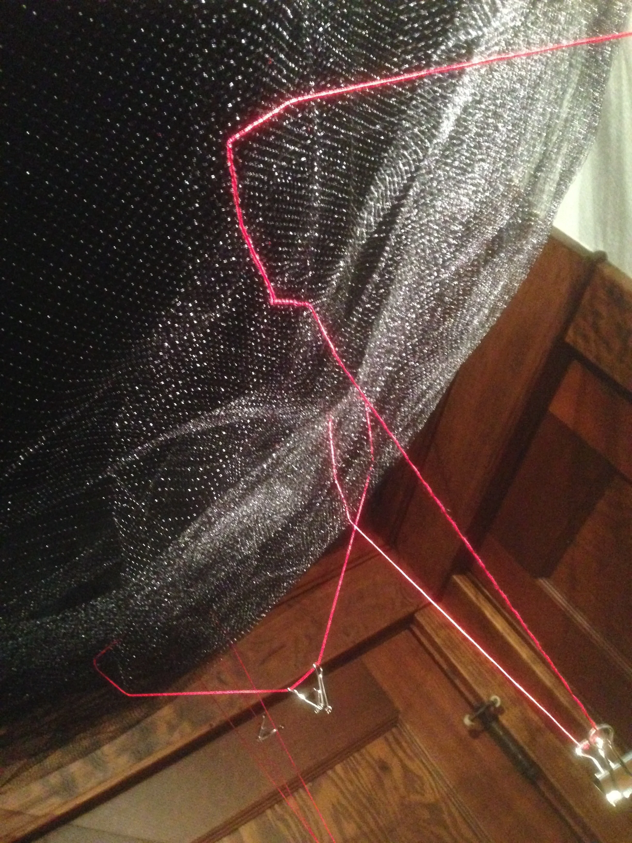  While I debated covering the walls with the black felt, I began hanging the black tulle from the ceiling&nbsp;and stitching the red crochet thread and silver binder clips through the material. I spent about six hours Monday December 1 doing this. Th