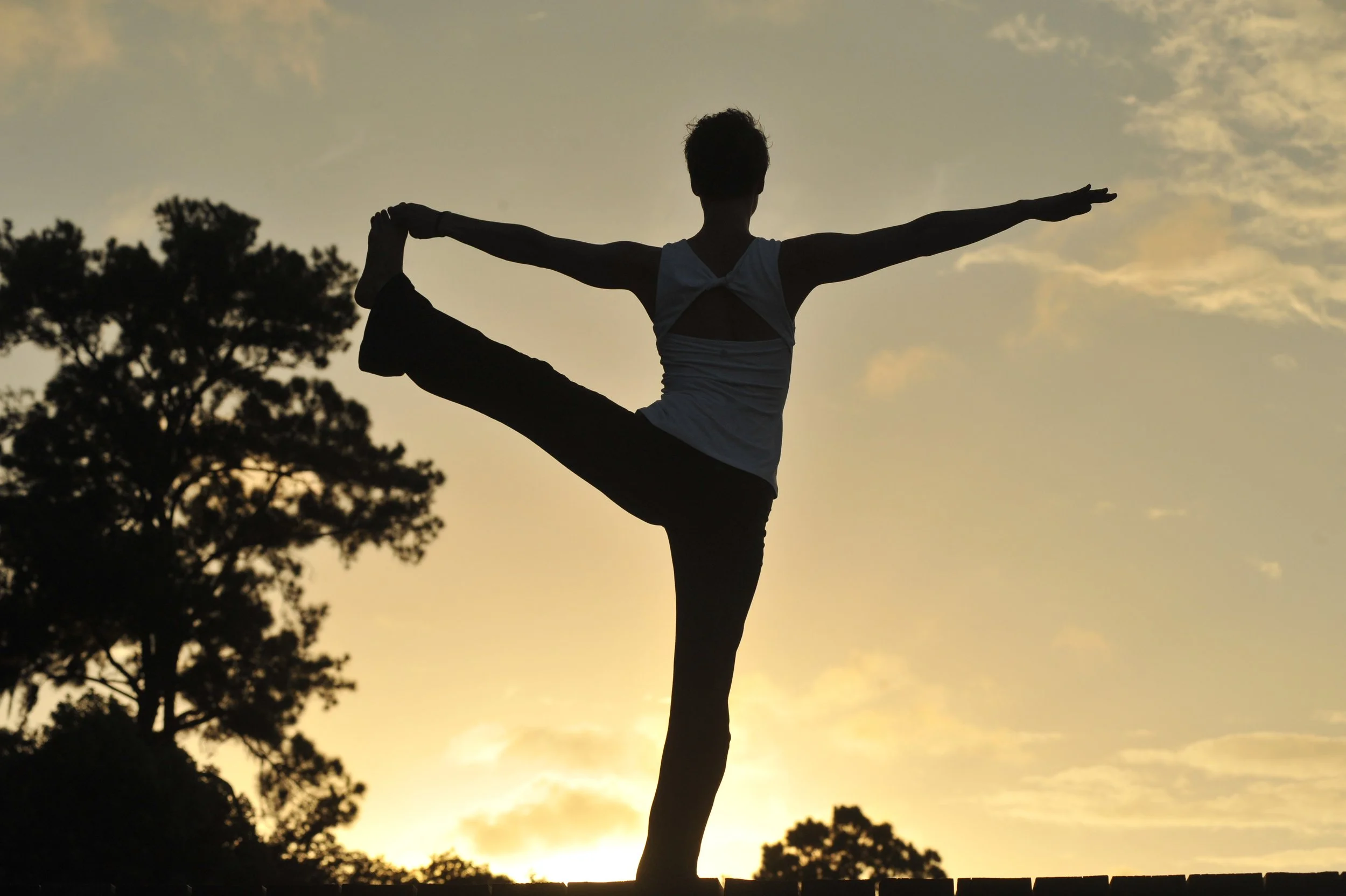 Chanda practices utthita pada hastasana on the dock at sunset