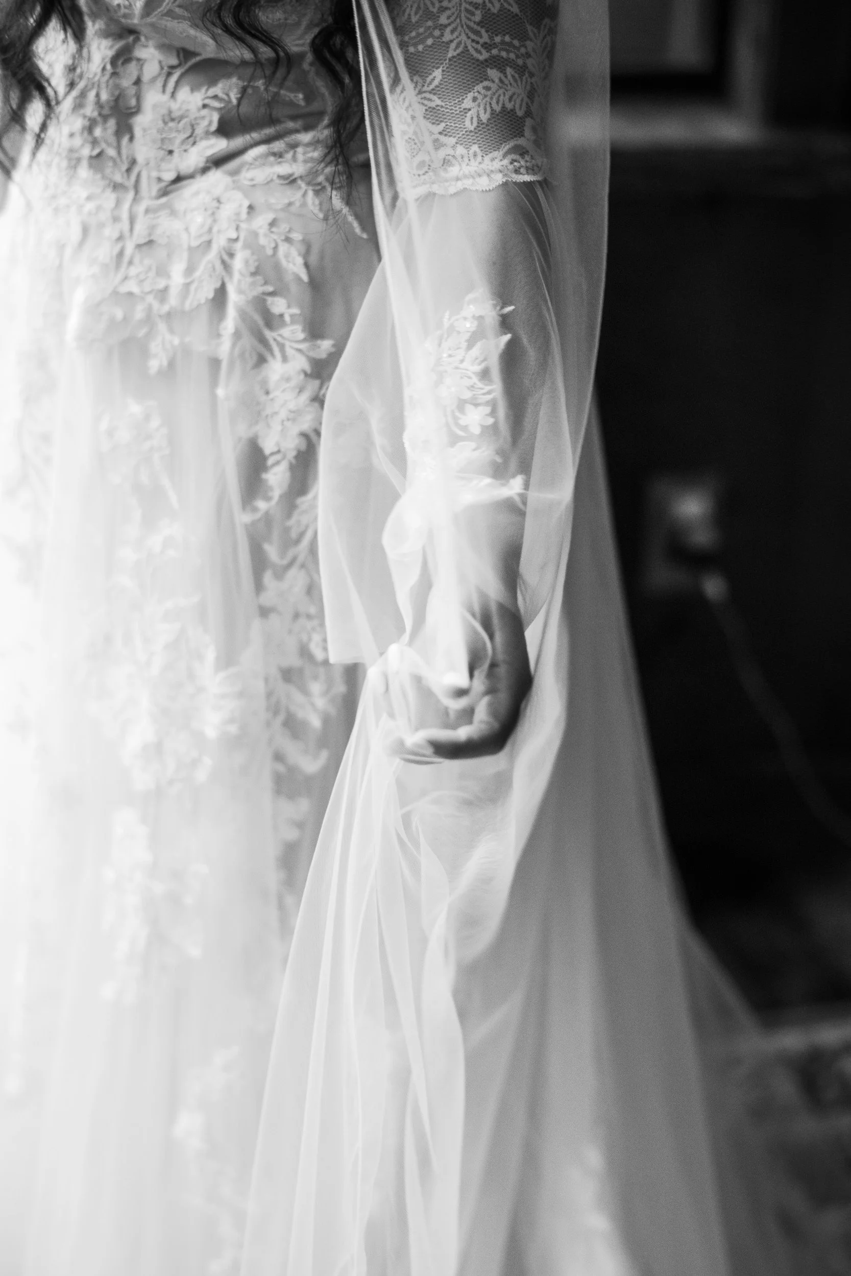 Bride running her hand through her veil in black and white