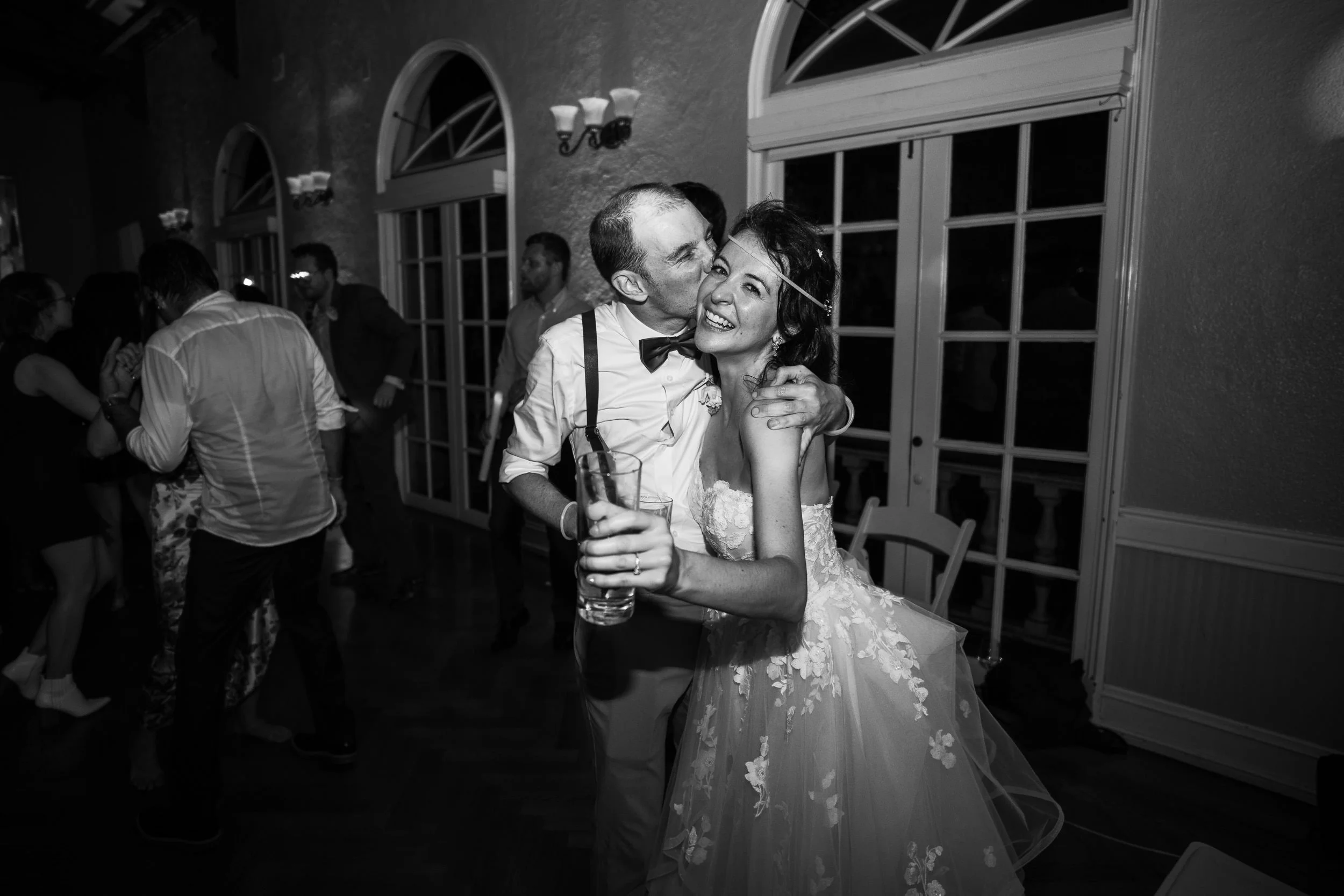 Groom gives his wife a kiss on the cheek during their wedding reception