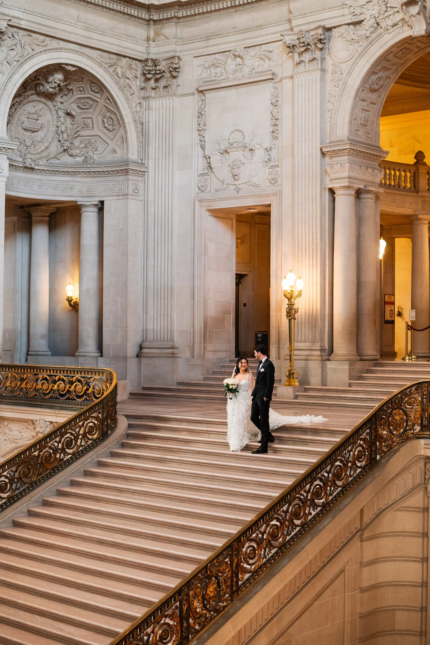 Bride and groom walking down the grand staircase at San Francisco City Hall