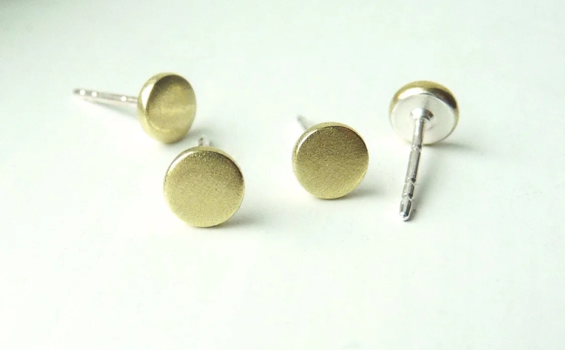 The backs are covered in silver. Enjoy brass without green ear lobes!