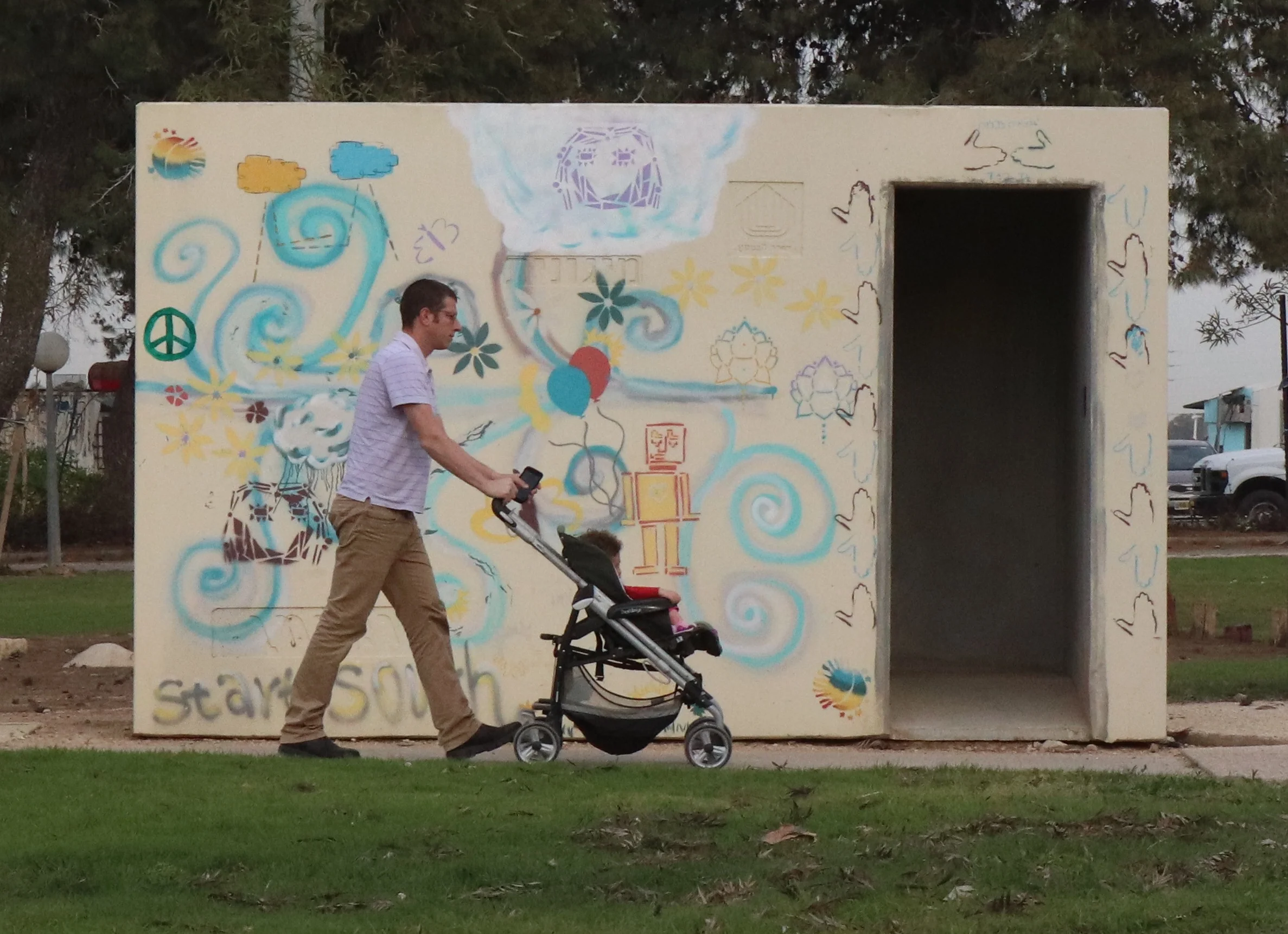 Man walks child past bomb shelter at Kibbutz Nahal Oz, on the border with Gaza.
