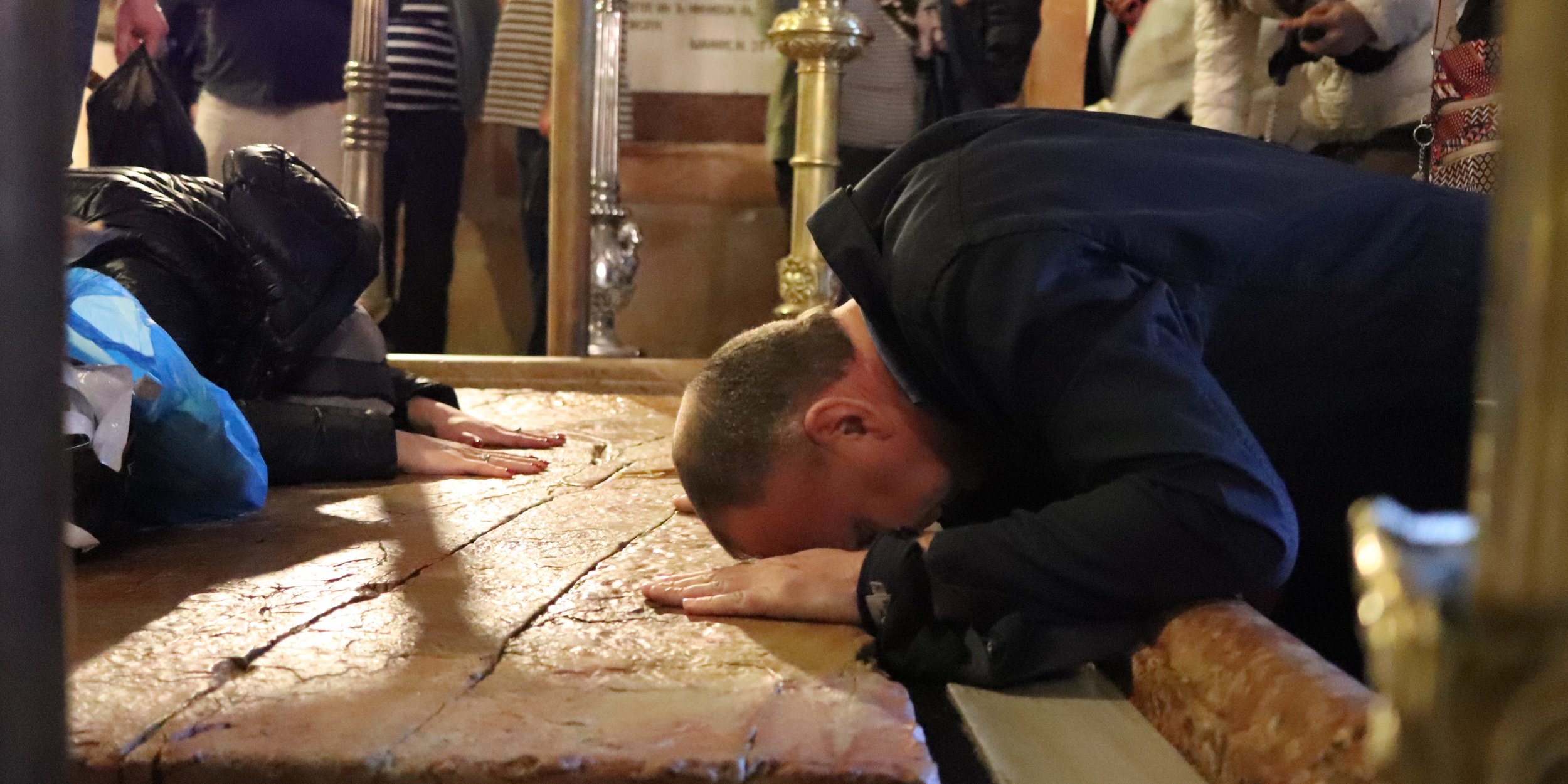 Believers pray at the stone where Jesus’ body lay after he was taken down from the cross.