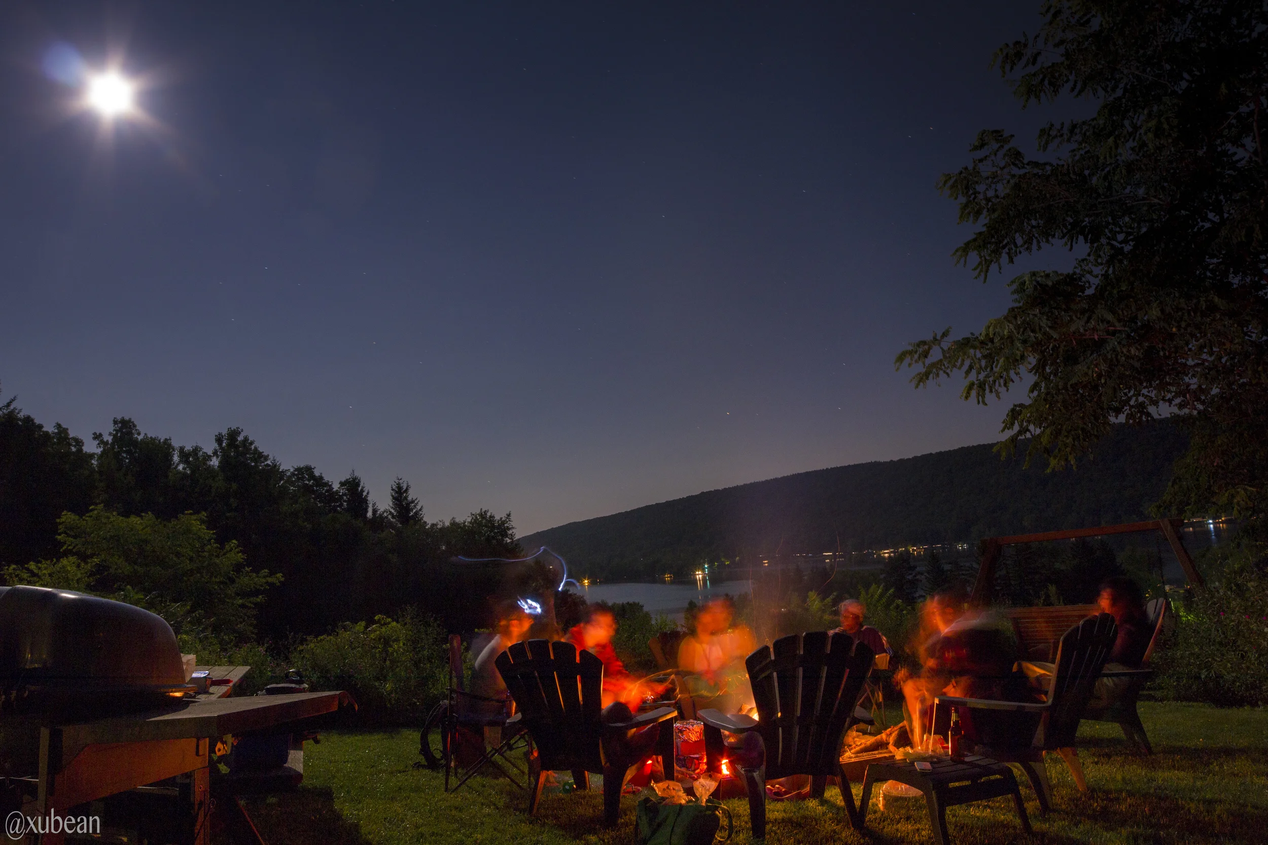 A group of friends camping over fire, under the moonlight
