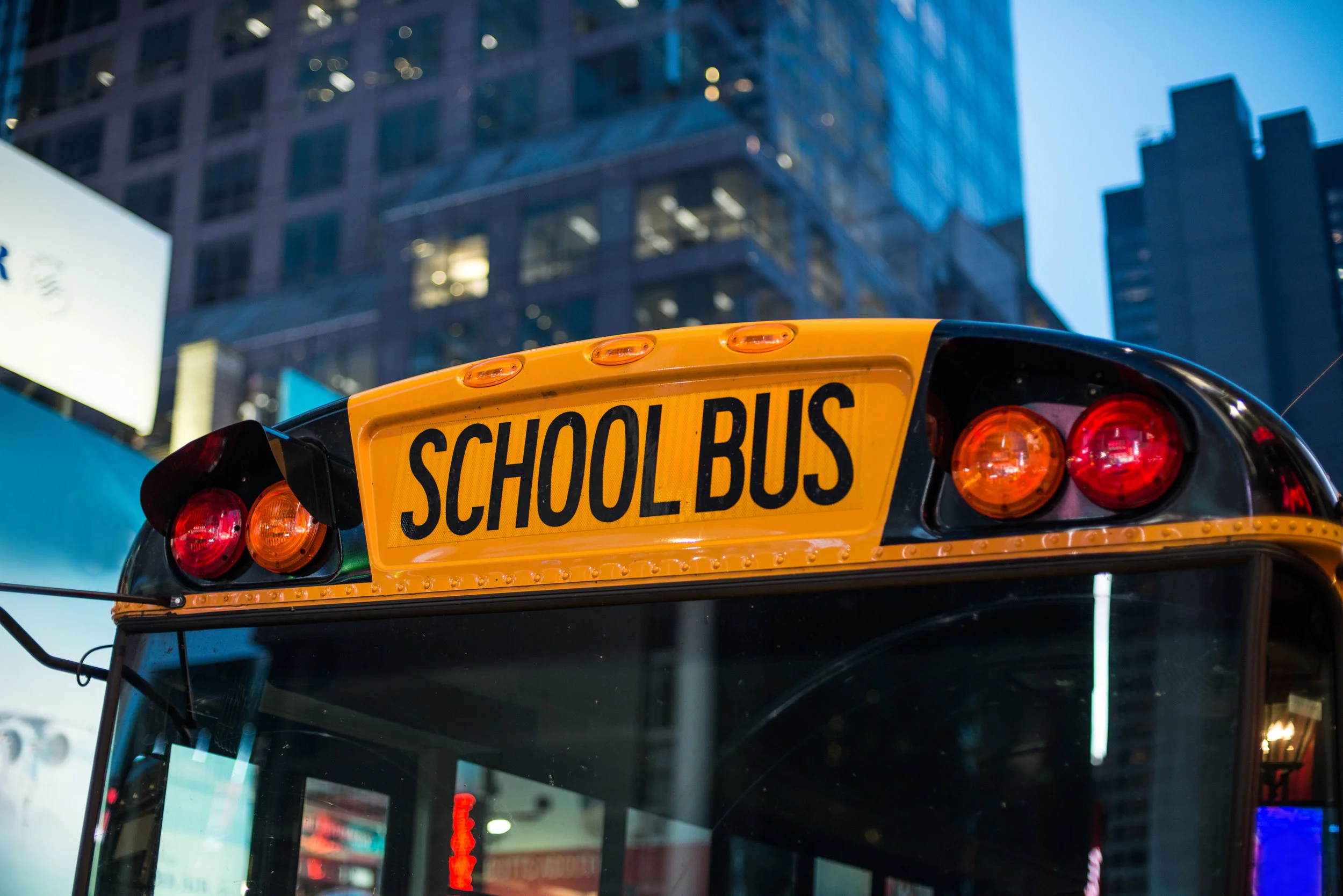 Image: A school bus drives through the city at night.