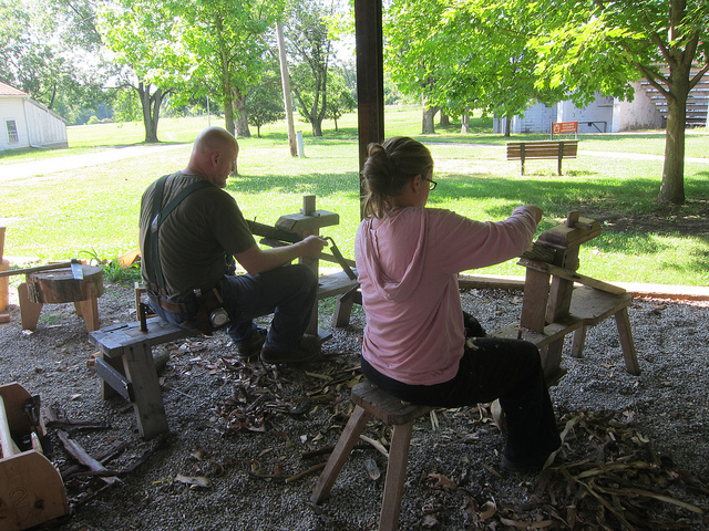 Rod Northcutt and Sam Senzek on shaving horses debarking the cordwood to reduce insect activity (photo by Sara Black)