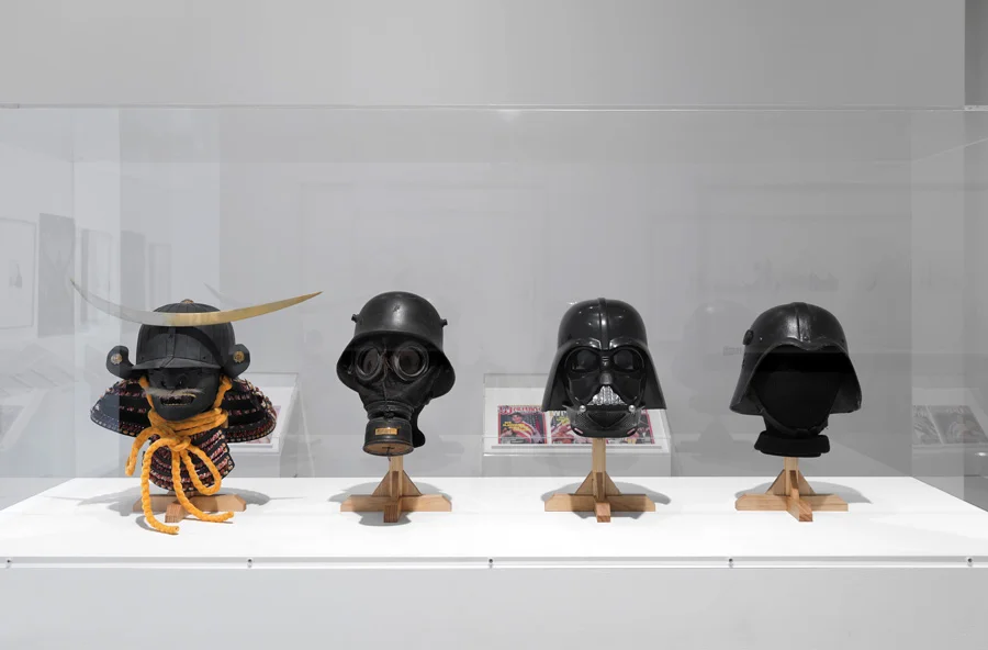 Next to these examples sit Darth Vader’s helmet and one of the Iraqi Fedayeen Saddam helmets, thus conveying a timeline where examples from the battlefield inspire a Hollywood filmic mythology, which in turns inspires armor found on the battlefield.