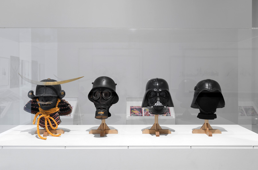   Next to these examples sit Darth Vader’s helmet and one of the Iraqi Fedayeen Saddam helmets, thus conveying a timeline where examples from the battlefield inspire a Hollywood filmic mythology, which in turns inspires armor found on the battlefield