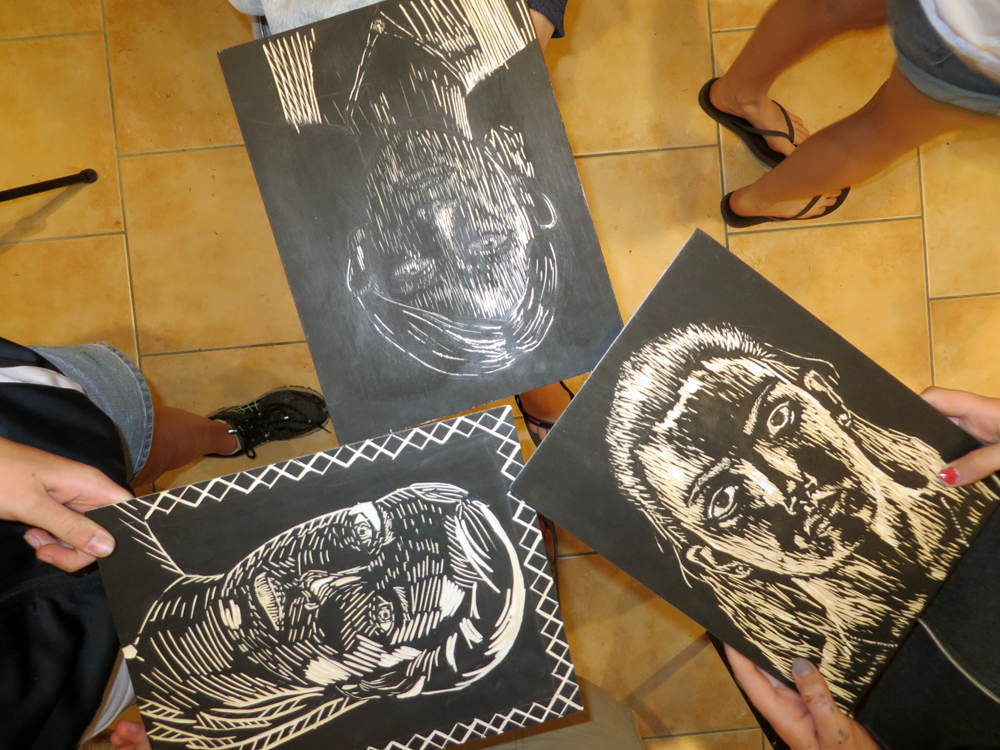 printmaking students showing off their woodcut self portraits les tapies summer programs