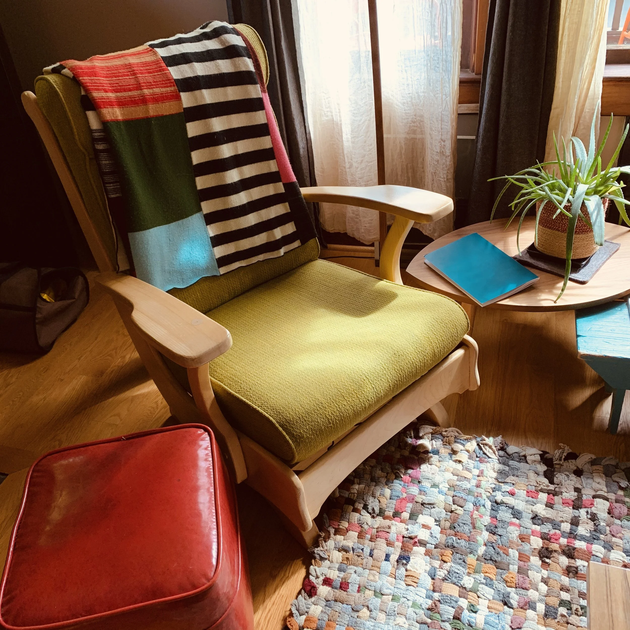 A colorful, cozy chair in Michele Greco’s Portland space, lit by morning light with a journal nearby.