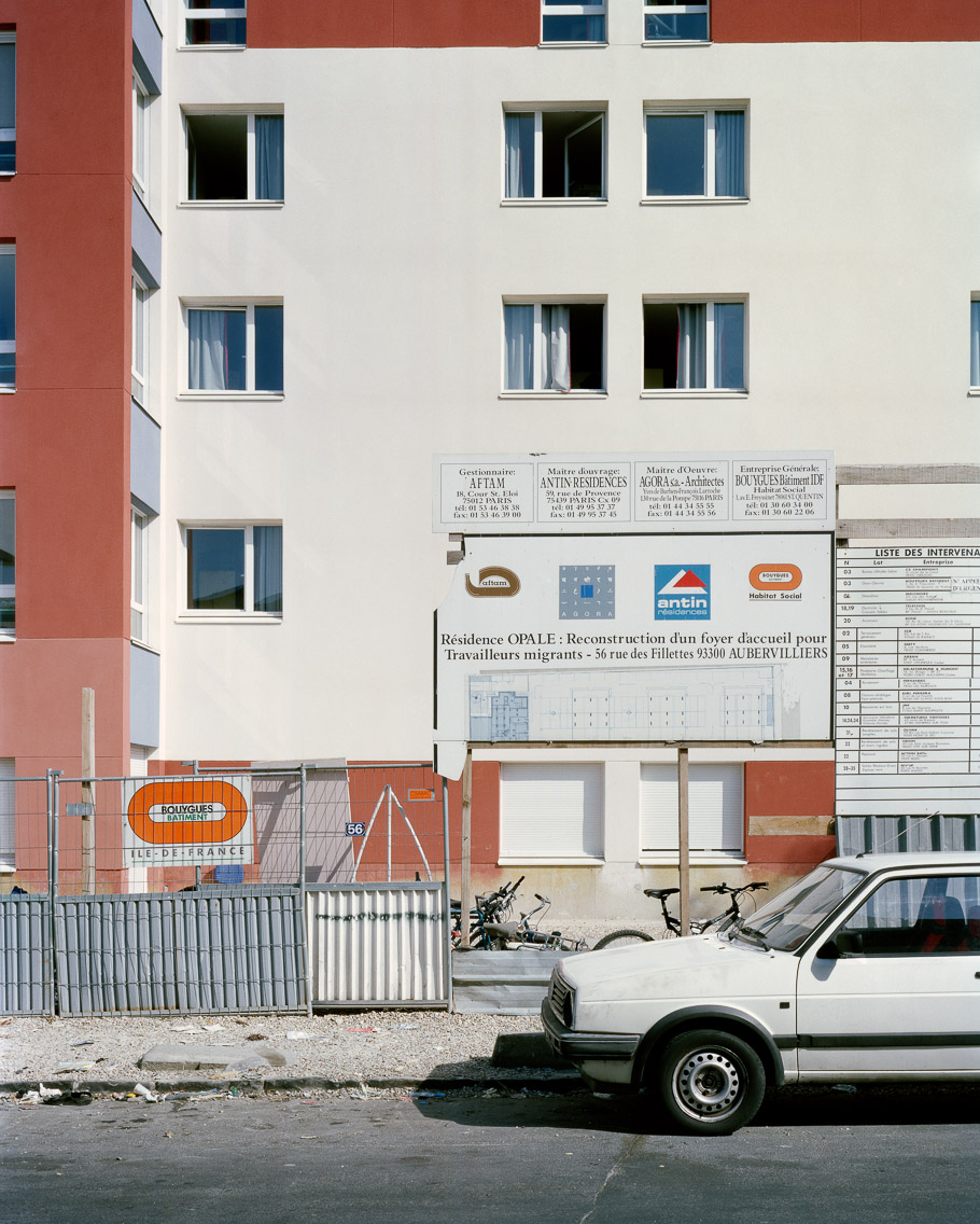   Banlieues #7  – &nbsp;Aubervilliers, Seine-Saint-Denis, 2006.   40"x50"    l'habitat marginalisé artist's statement   Eleven months after the riots, this construction of this “Welcome House” for migrant workers may represent French government effor