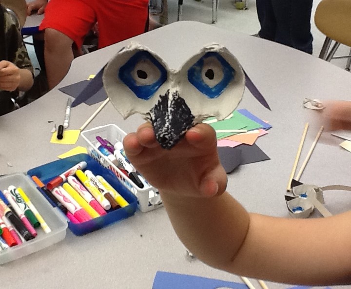 A student shows off their dog rod puppet in process.