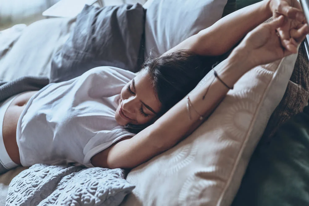young woman stretching in bed.jpg