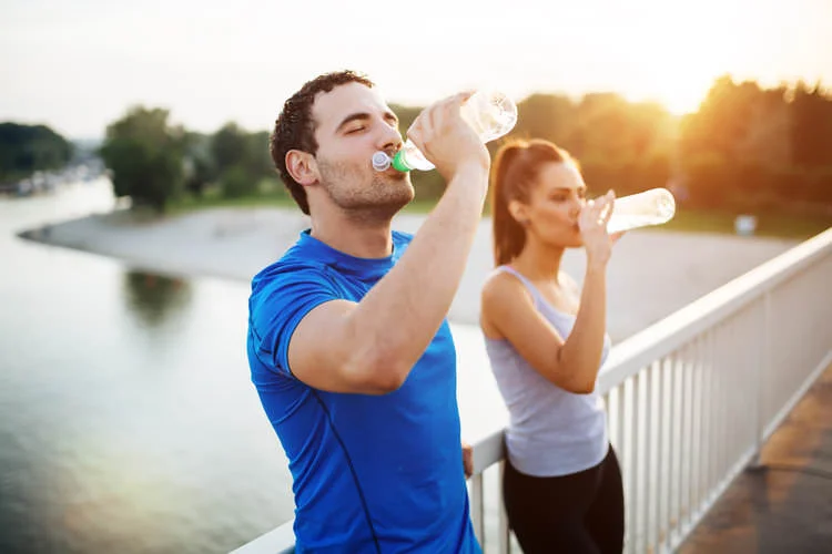 couple drinking water while standing on bridge.jpg
