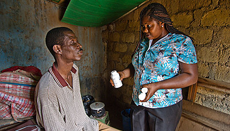 Agnes Onydo conducts a home visit with Jayo Benjamin. Since he lost his sight, he needs help around his home and to stick to his HIV drug regimen. Photo by Karen Kasmauski for CRS.