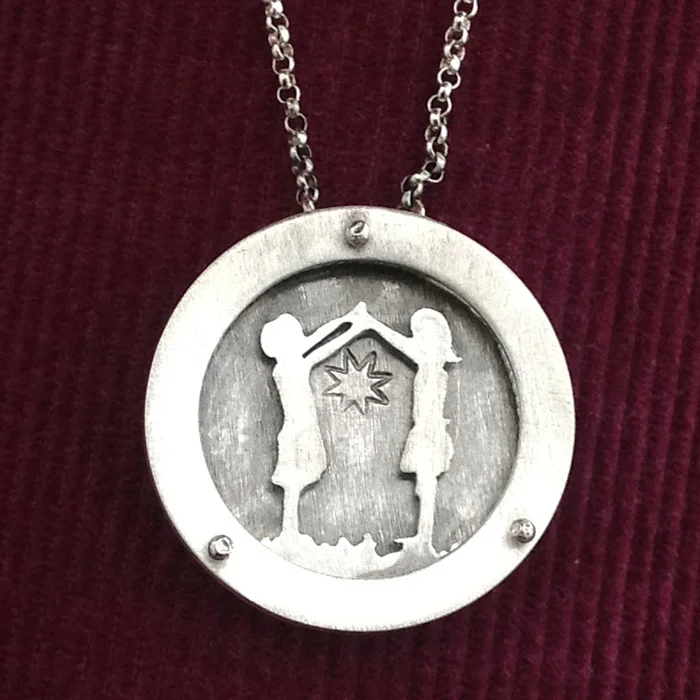 Large circle shadowbox necklace of two girls holding hands.