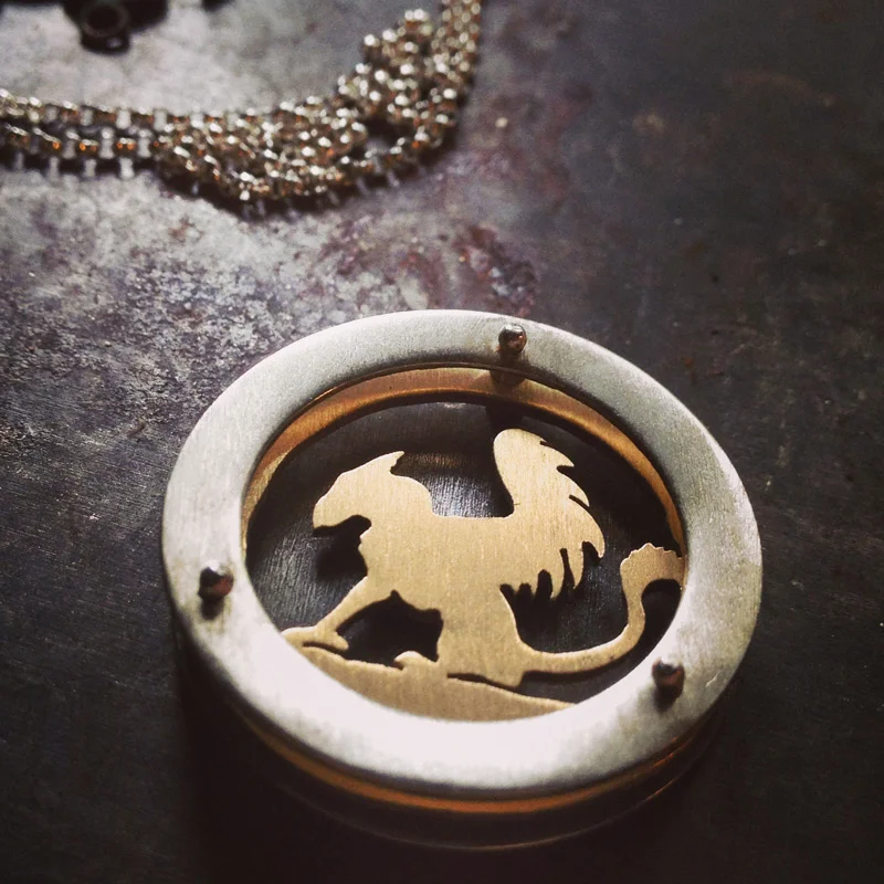 Large circle shadowbox necklace with 10k gold griffin as center design and gold fill chain.
