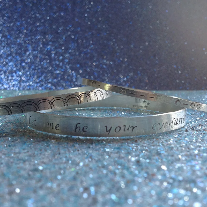 Gift set of three hand stamped sterling silver bangles. One with song lyrics, one with geometric design and one with braille coding.