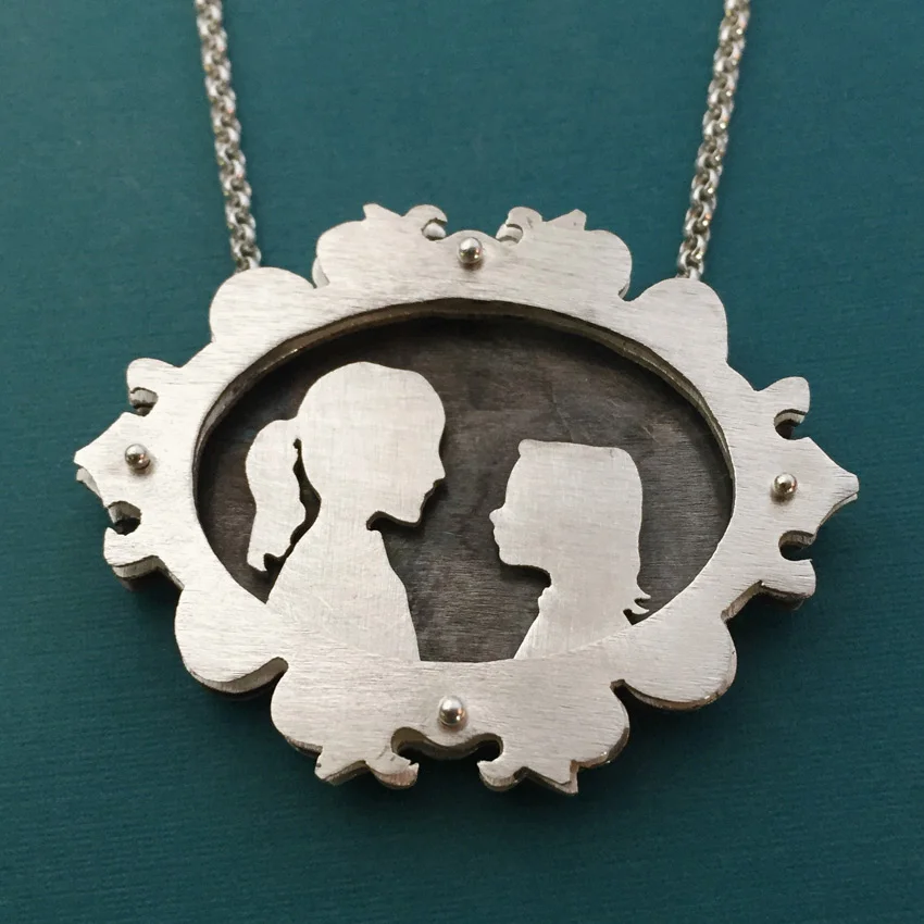 Ornate shadowbox necklace with silhouette of children.