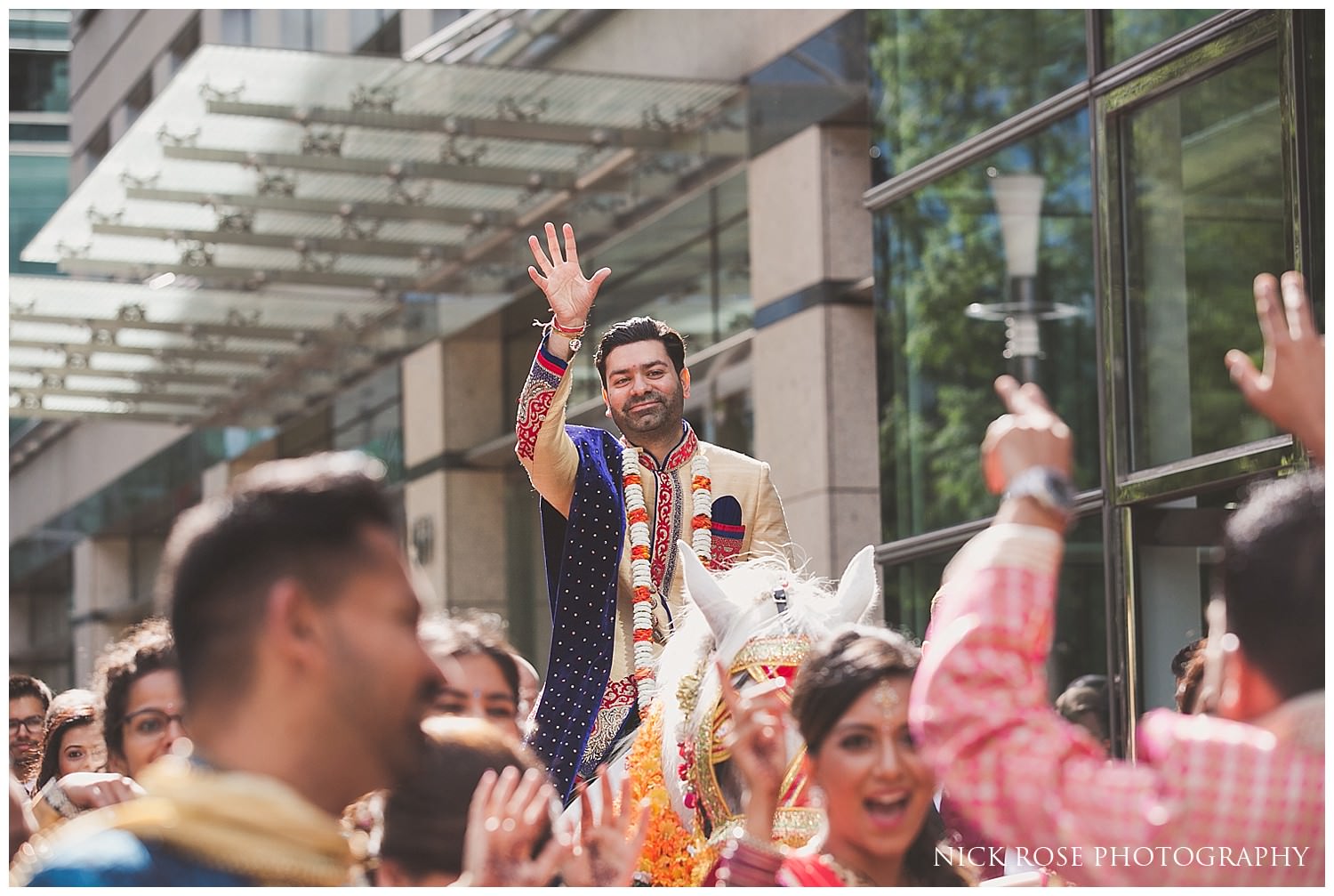  Groom on a hindu horse with his hands in the air for his Indian Baraat entrance in London 