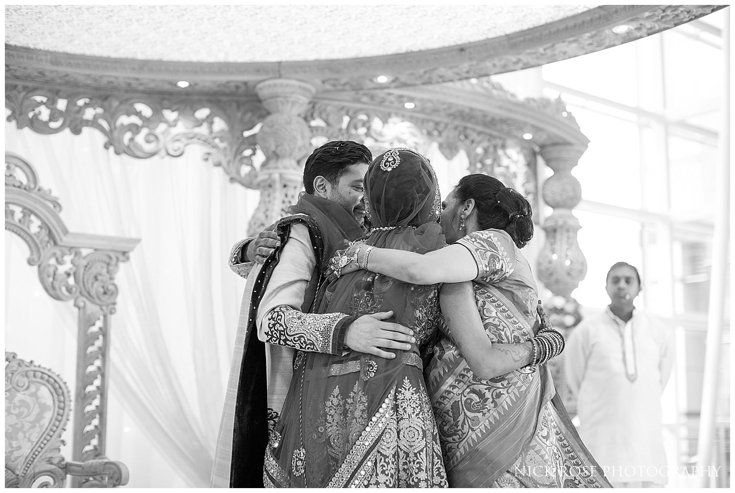 Family hugging during an Asian Hindu wedding in the East Wintergarden at Canary Wharf London 