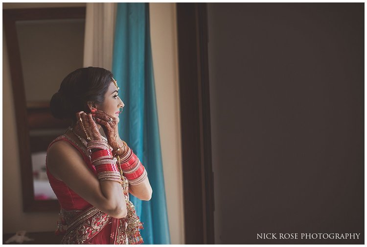  Asian bride putting on earrings before her destination Hindu wedding in Dubai 