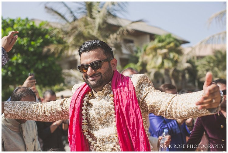  Indian groom wearing a pink scarf making his beach wedding ceremony entrance at the Sofitel Palm Dubai 