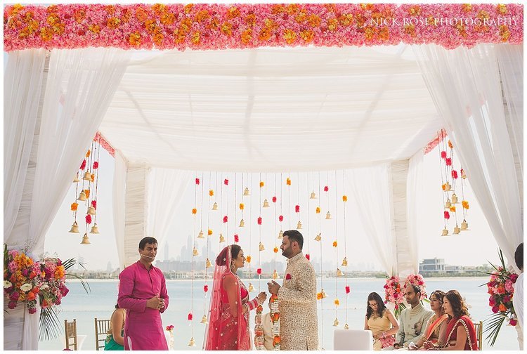 Bride and groom standing under a Hindu wedding mandap exchanging garlands at the Sofitel Palm Dubai