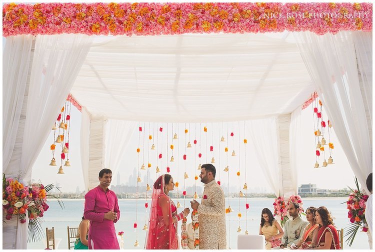  Bride and groom standing under a Hindu wedding mandap exchanging garlands at the Sofitel Palm Dubai 