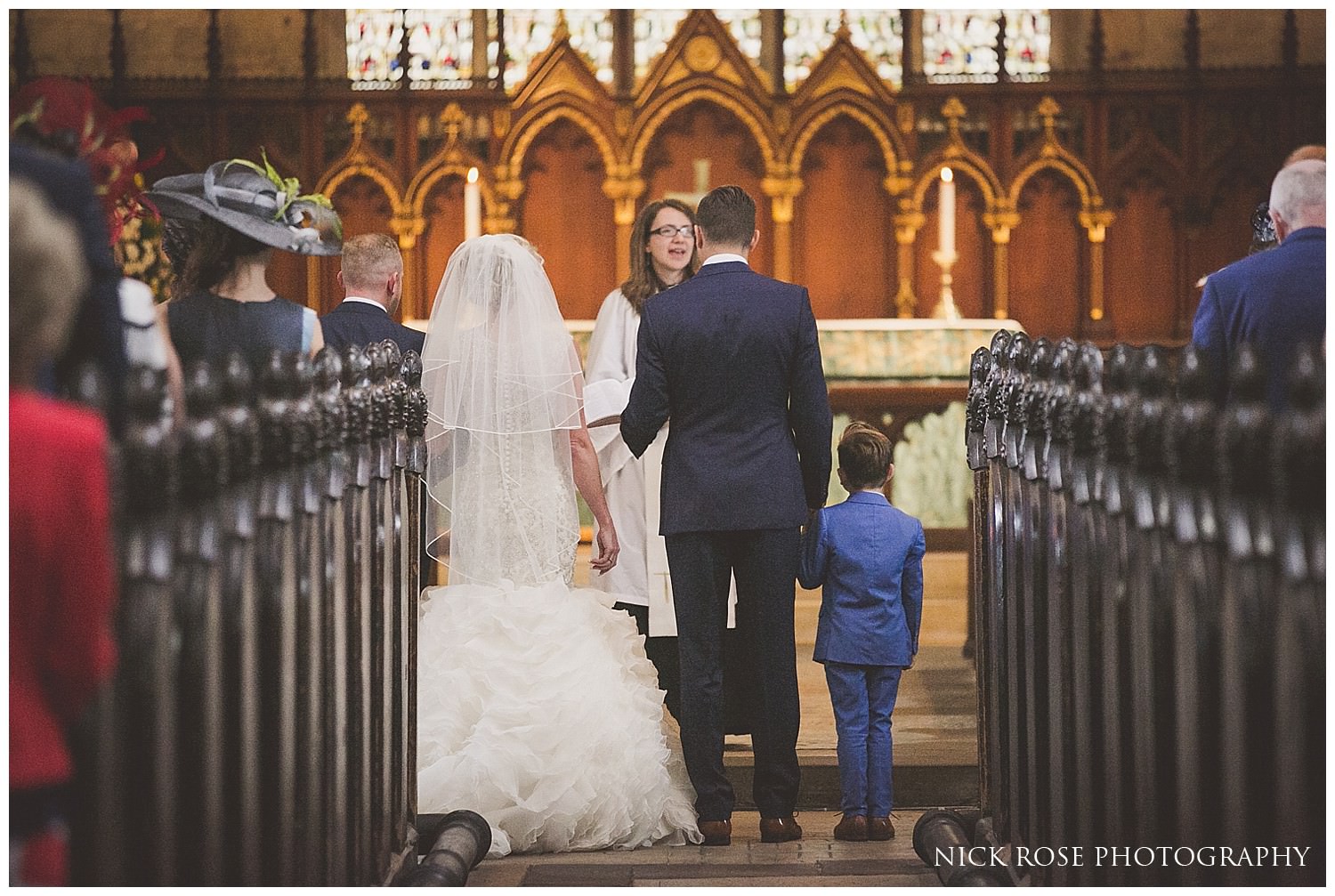  Bride and groom with son holding hands during a Tickhill wedding ceremony at St Mary's church in Yorkshire 