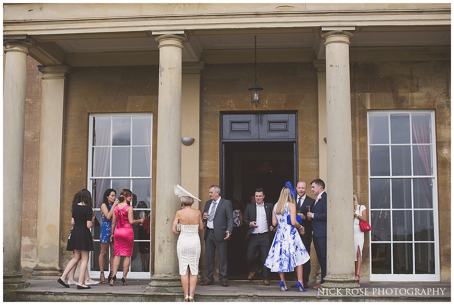  Guests standing outside under the columns for a Rudding Park wedding in Harrogate 